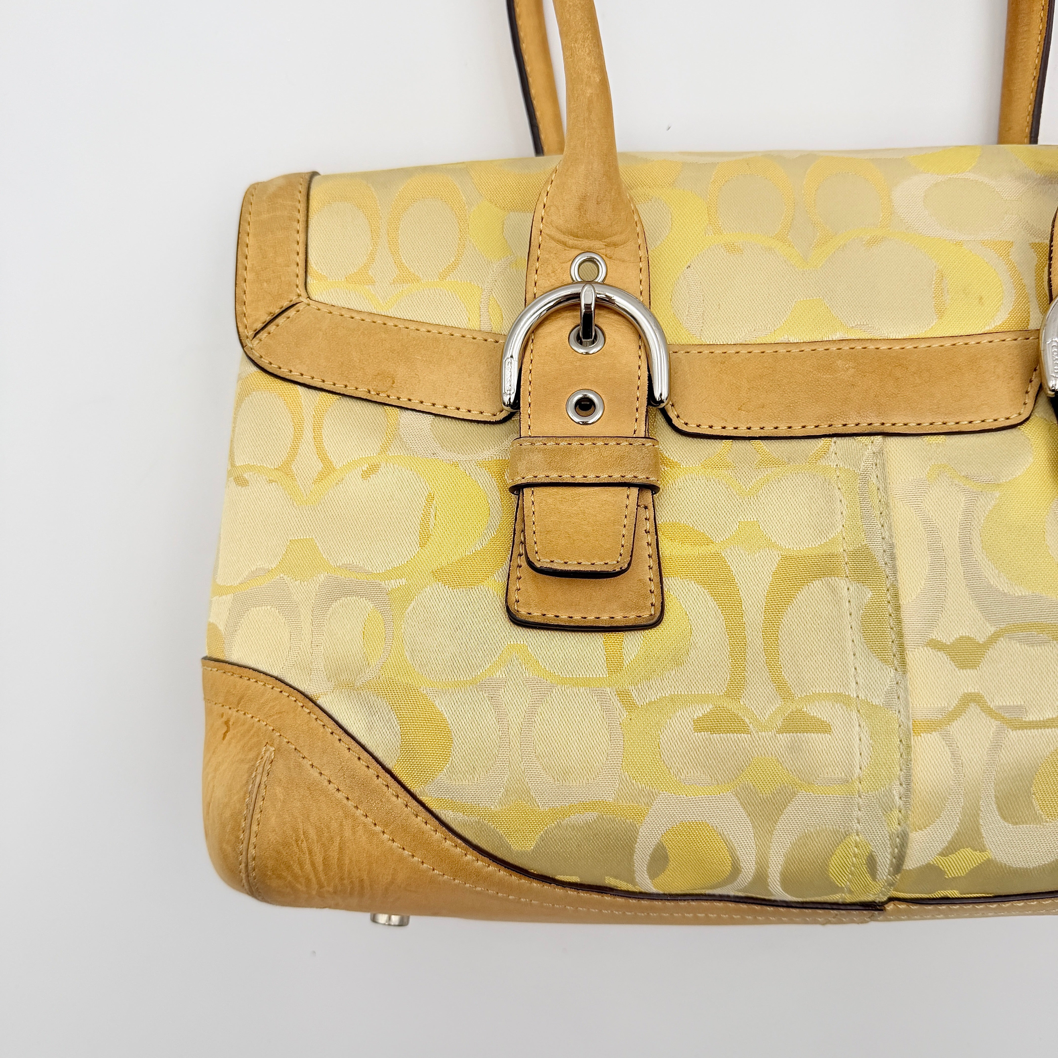 Coach Soho shoulder bag in yellow signature optic fabric with tan leather trim and silver hardware, shown with double handles.