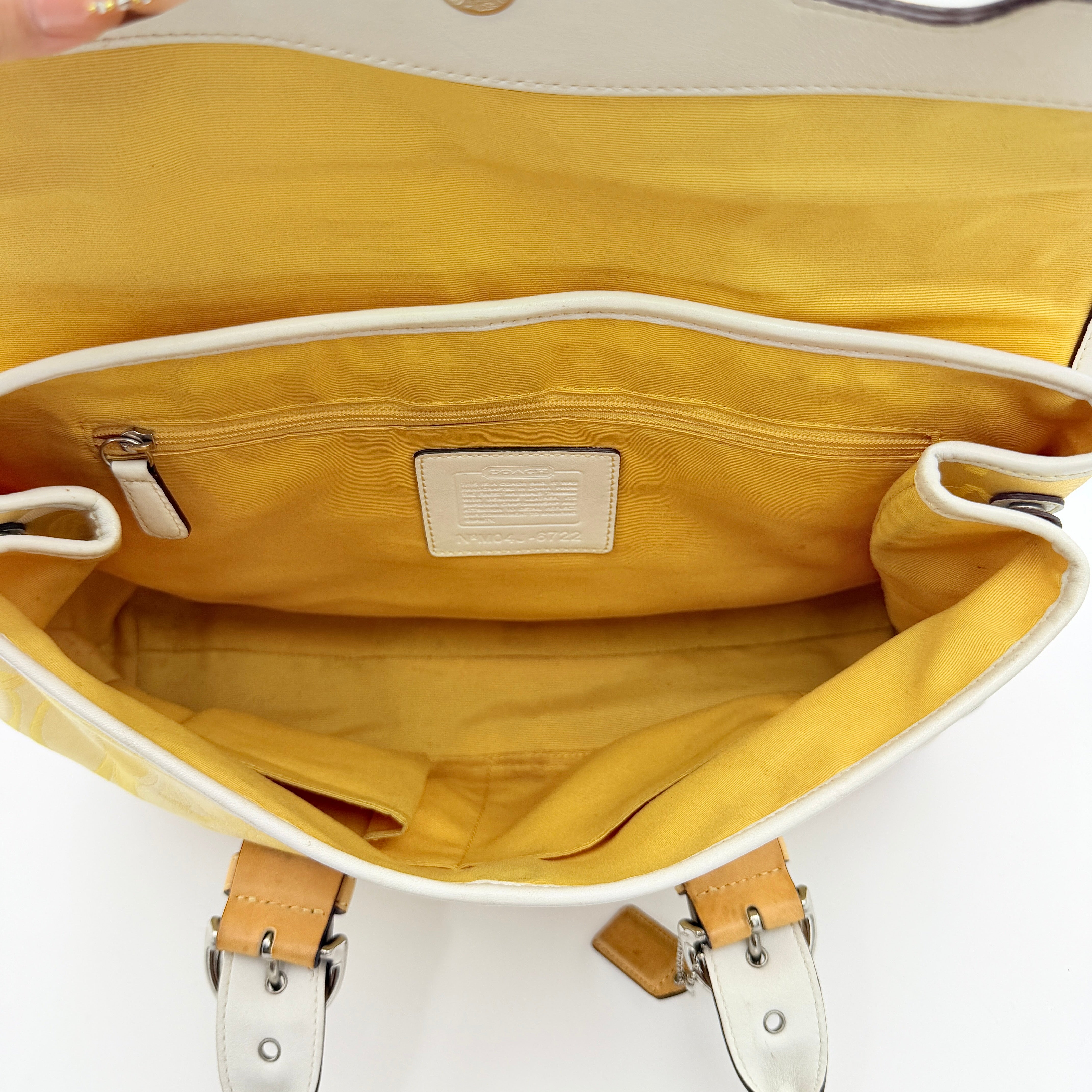 Coach Soho shoulder bag in yellow signature optic fabric with tan leather trim and silver hardware, shown with double handles.