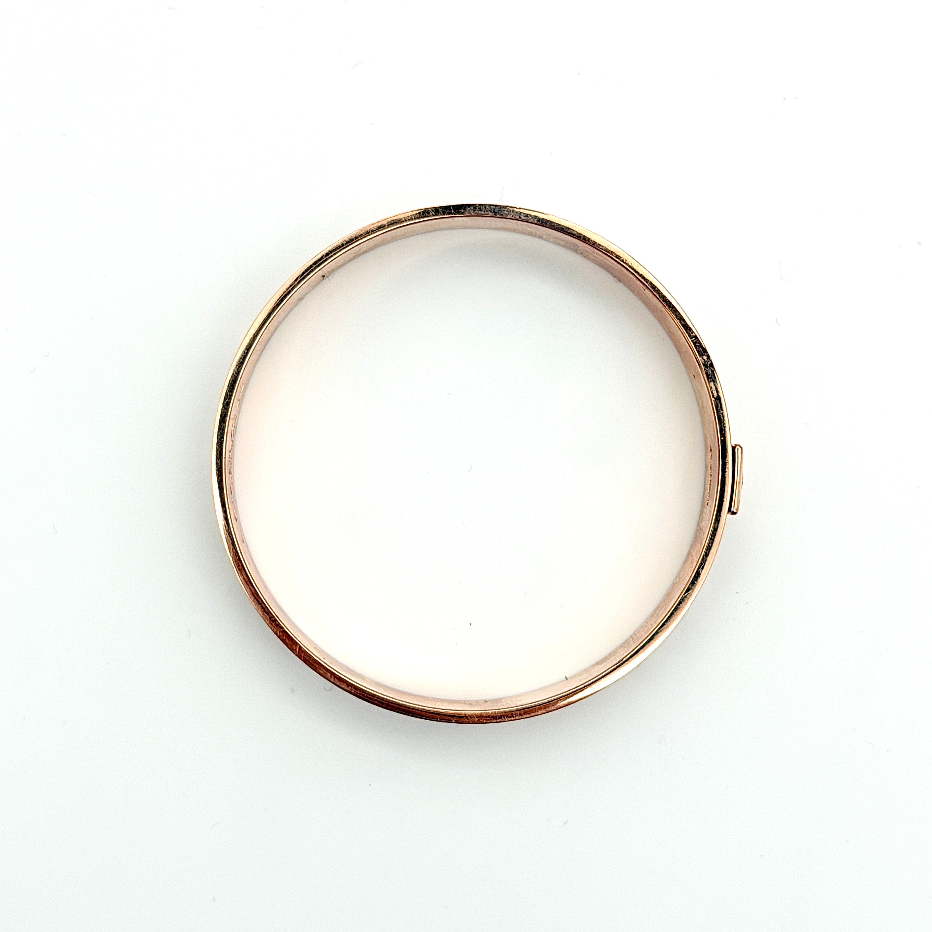Coach rose gold bangle bracelet with signature enamel design, photographed with original box.