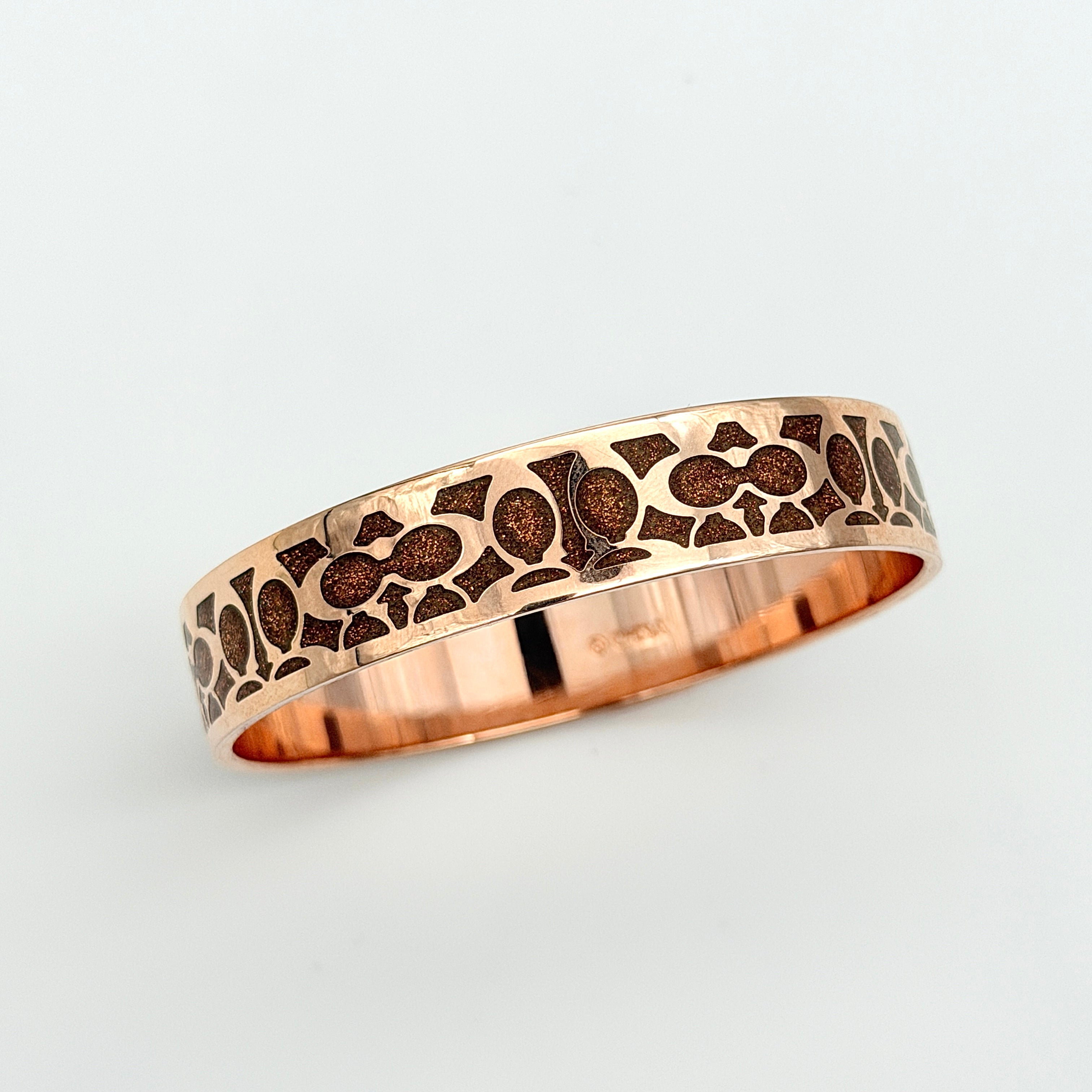 Coach rose gold bangle bracelet with signature enamel design, photographed with original box.