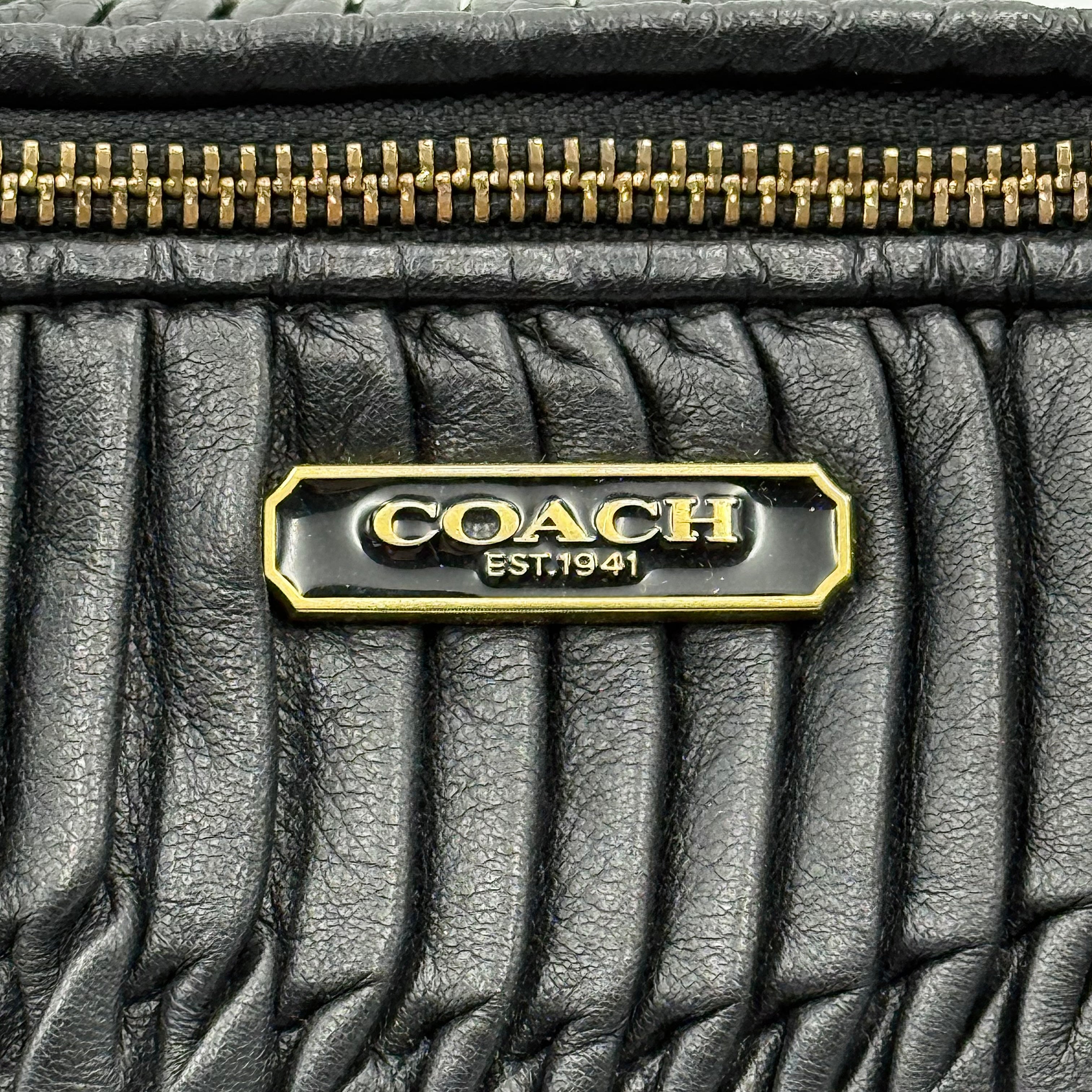 Coach Signature Madison shoulder bag in pleated black leather with gold hardware and dual handles.
