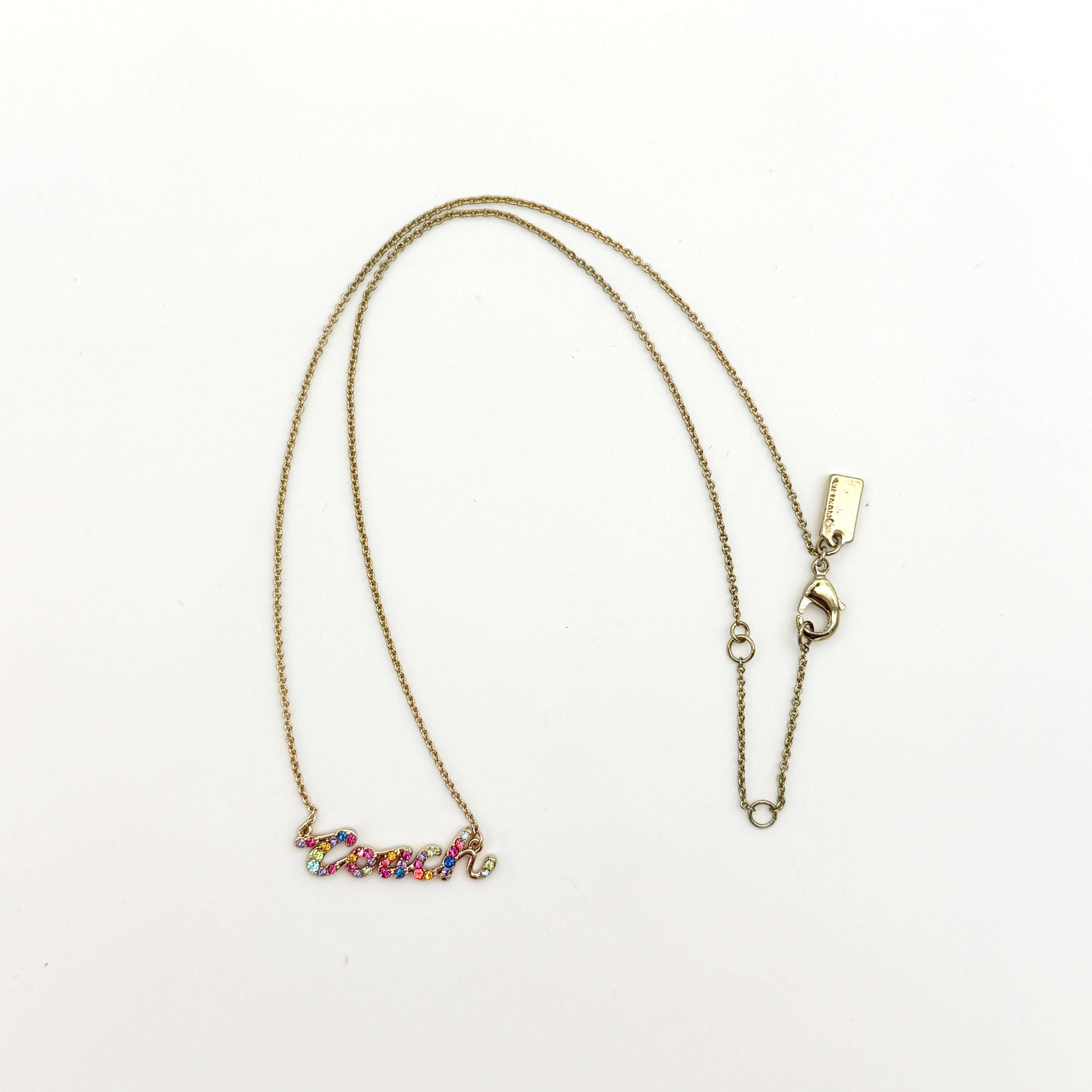 Coach Signature Script Rainbow Necklace with multicolour crystals set on a gold-tone chain, displayed in its original Coach box.