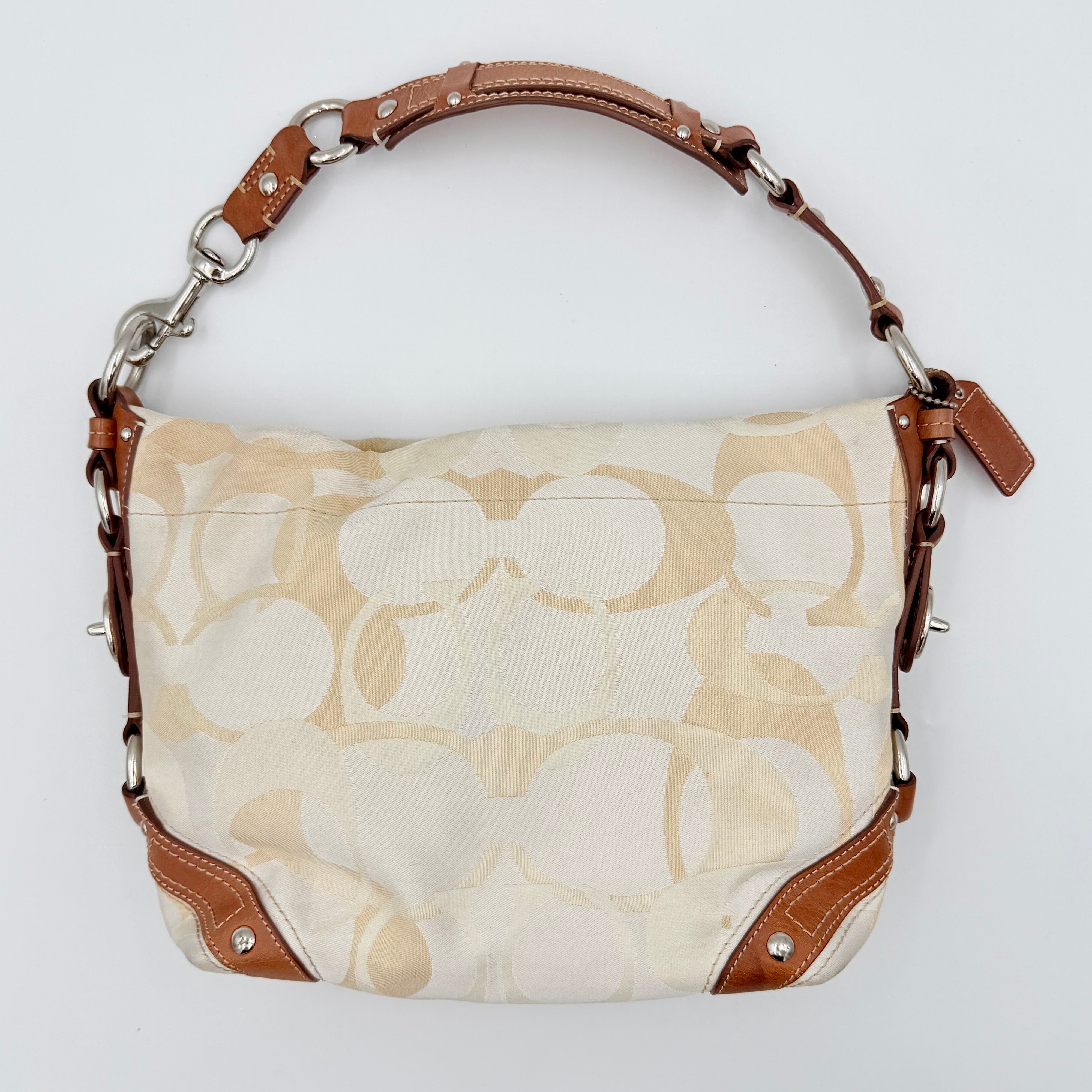 Coach Signature Carly Hobo shoulder bag in cream and brown canvas with tan leather trim and chain-detailed strap.