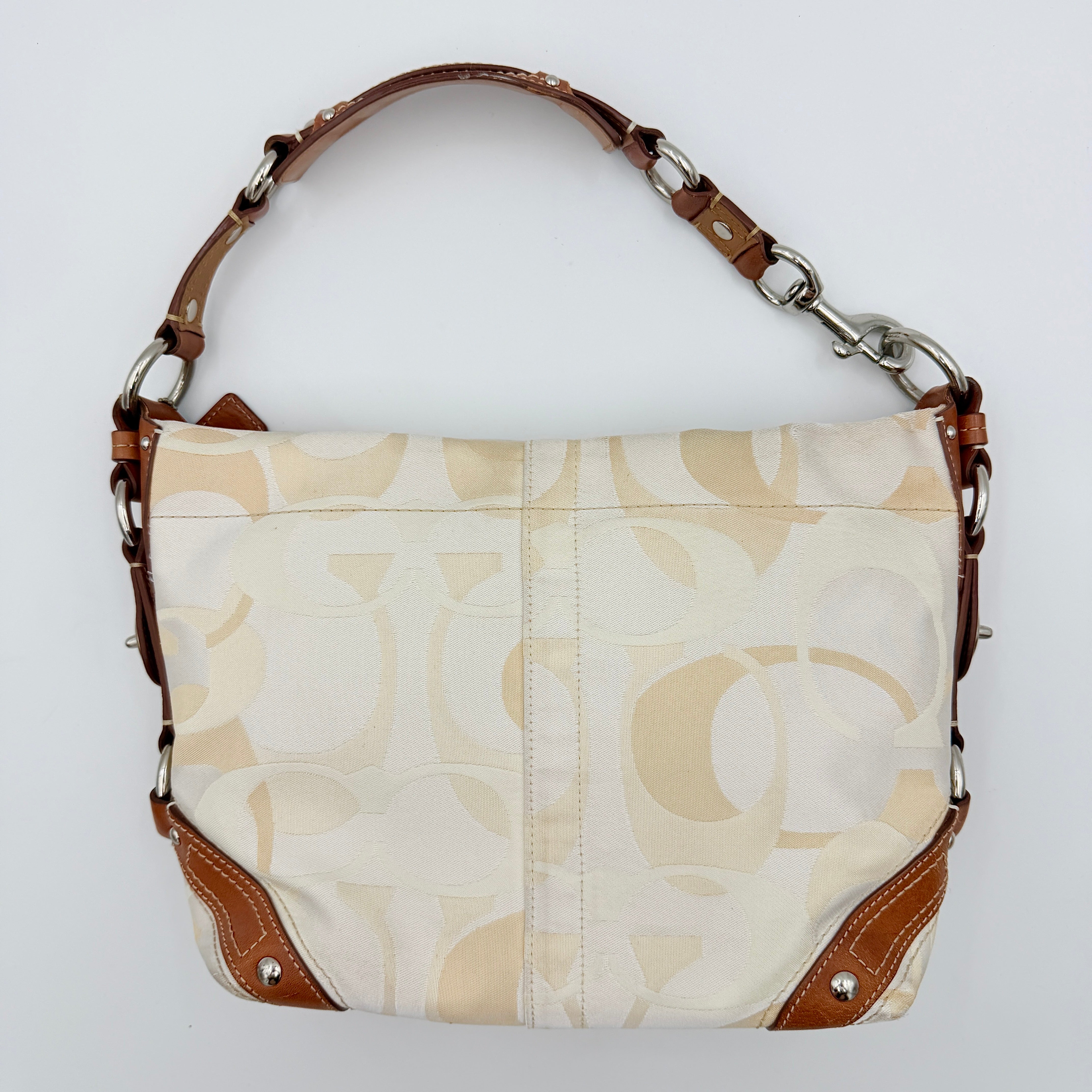 Coach Signature Carly Hobo shoulder bag in cream and brown canvas with tan leather trim and chain-detailed strap.