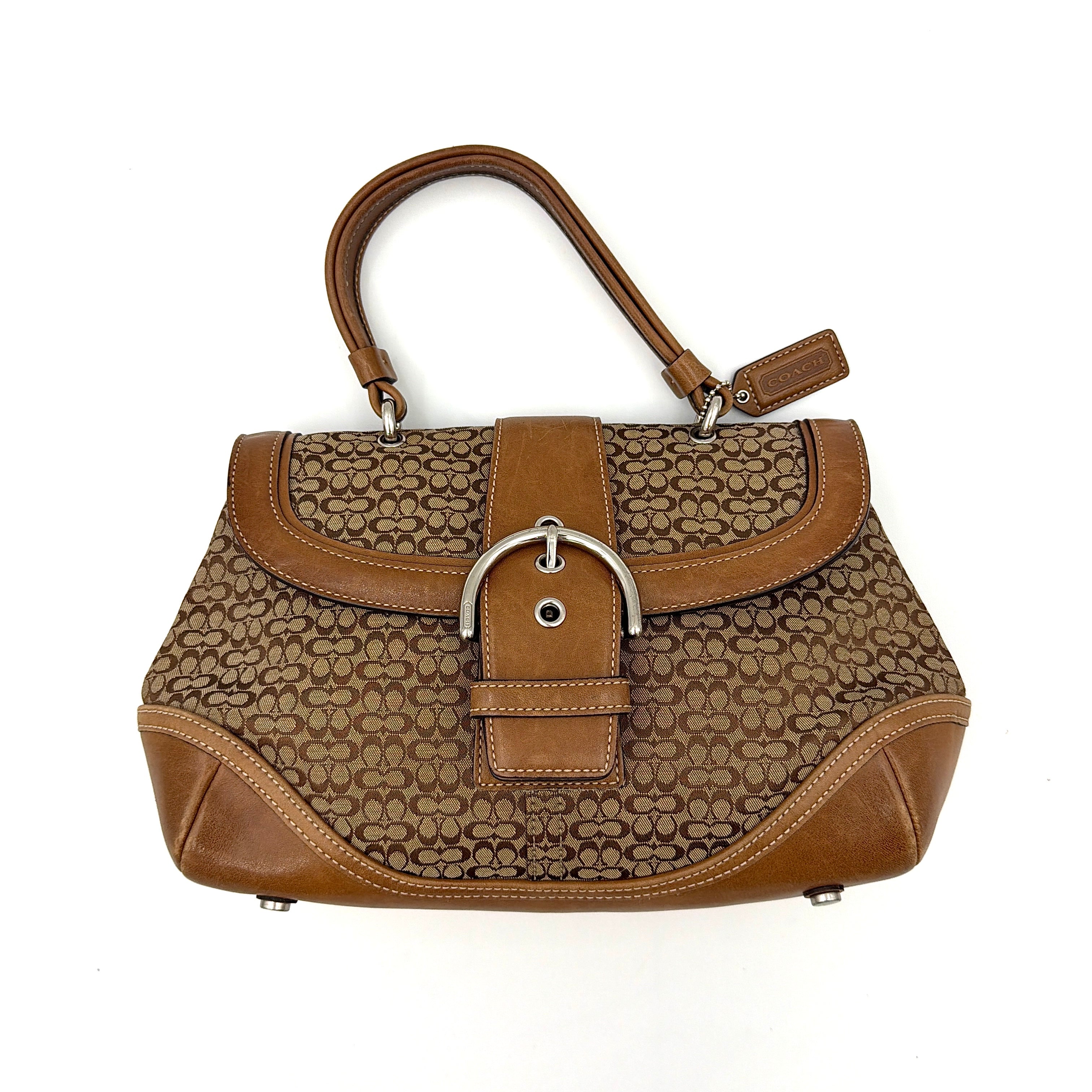 Coach Soho Shoulder Bag in beige and tan monogram jacquard with caramel leather trim, featuring silver hardware and a signature buckle flap.