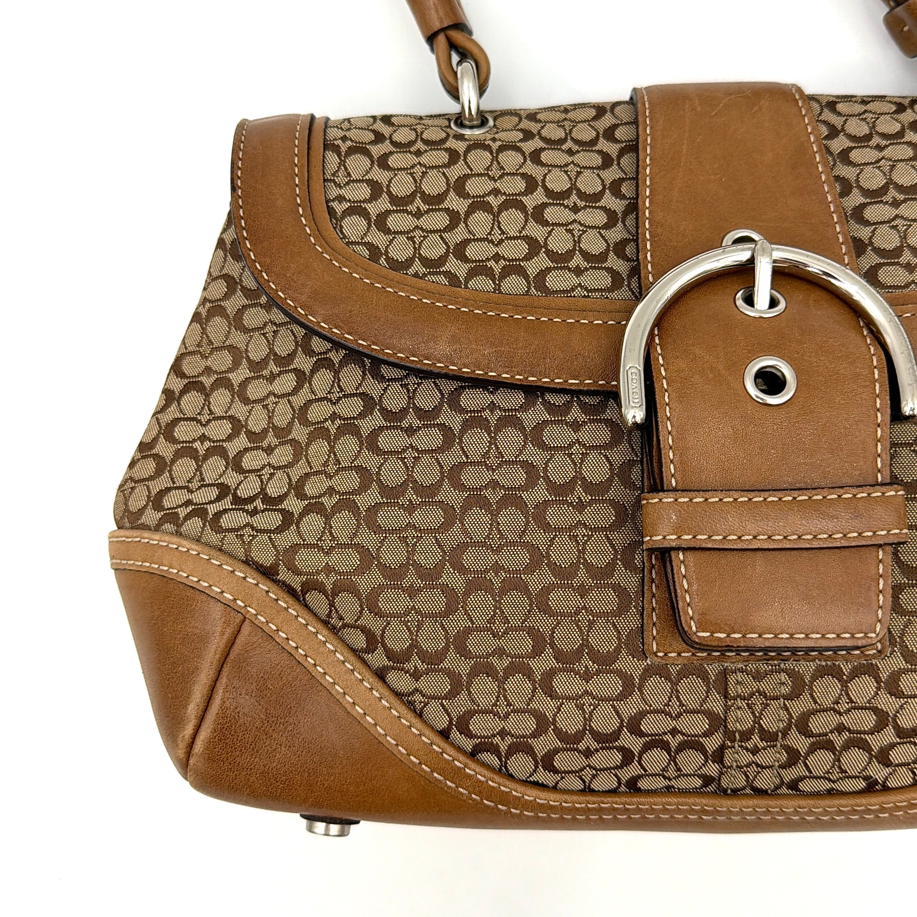 Coach Soho Shoulder Bag in beige and tan monogram jacquard with caramel leather trim, featuring silver hardware and a signature buckle flap.