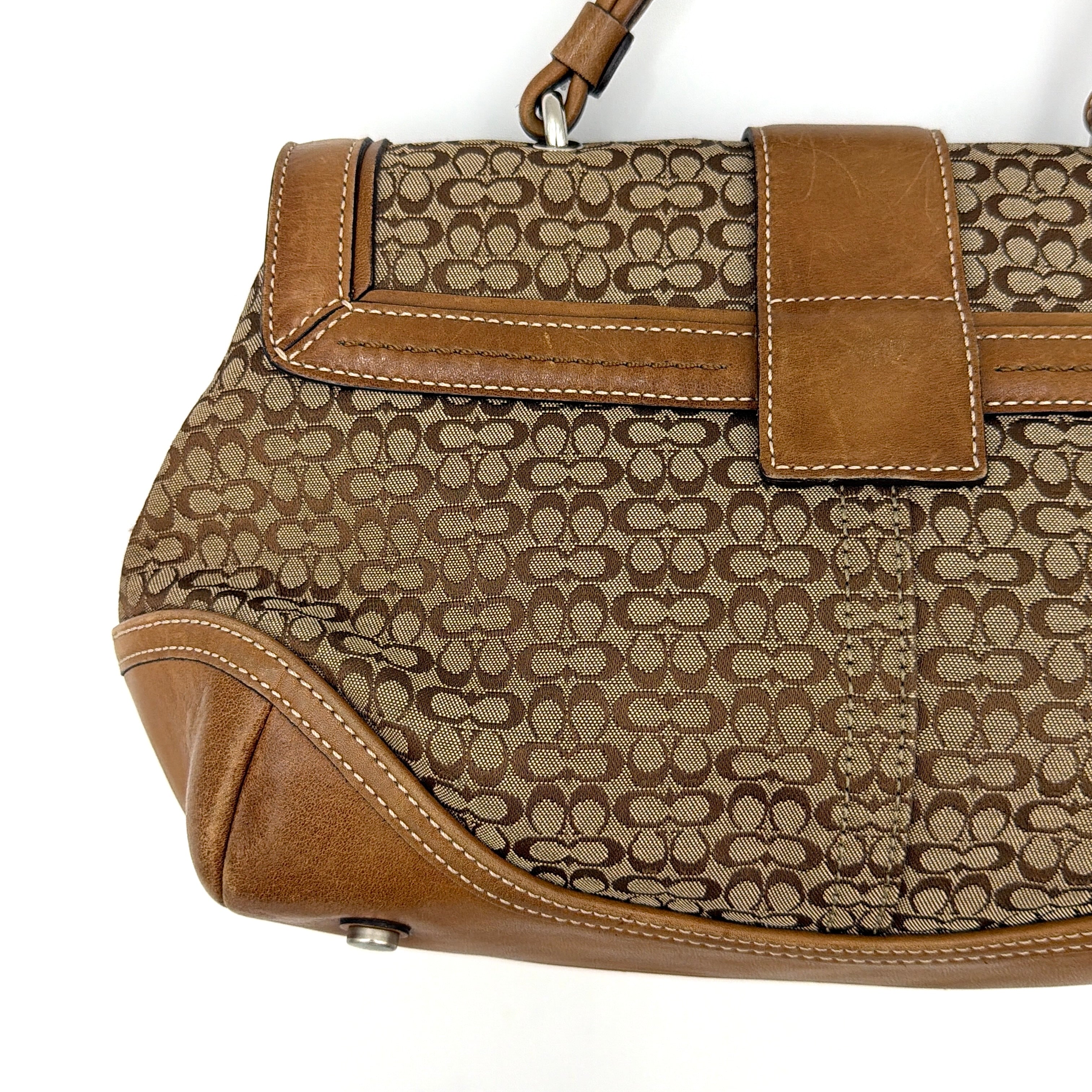 Coach Soho Shoulder Bag in beige and tan monogram jacquard with caramel leather trim, featuring silver hardware and a signature buckle flap.