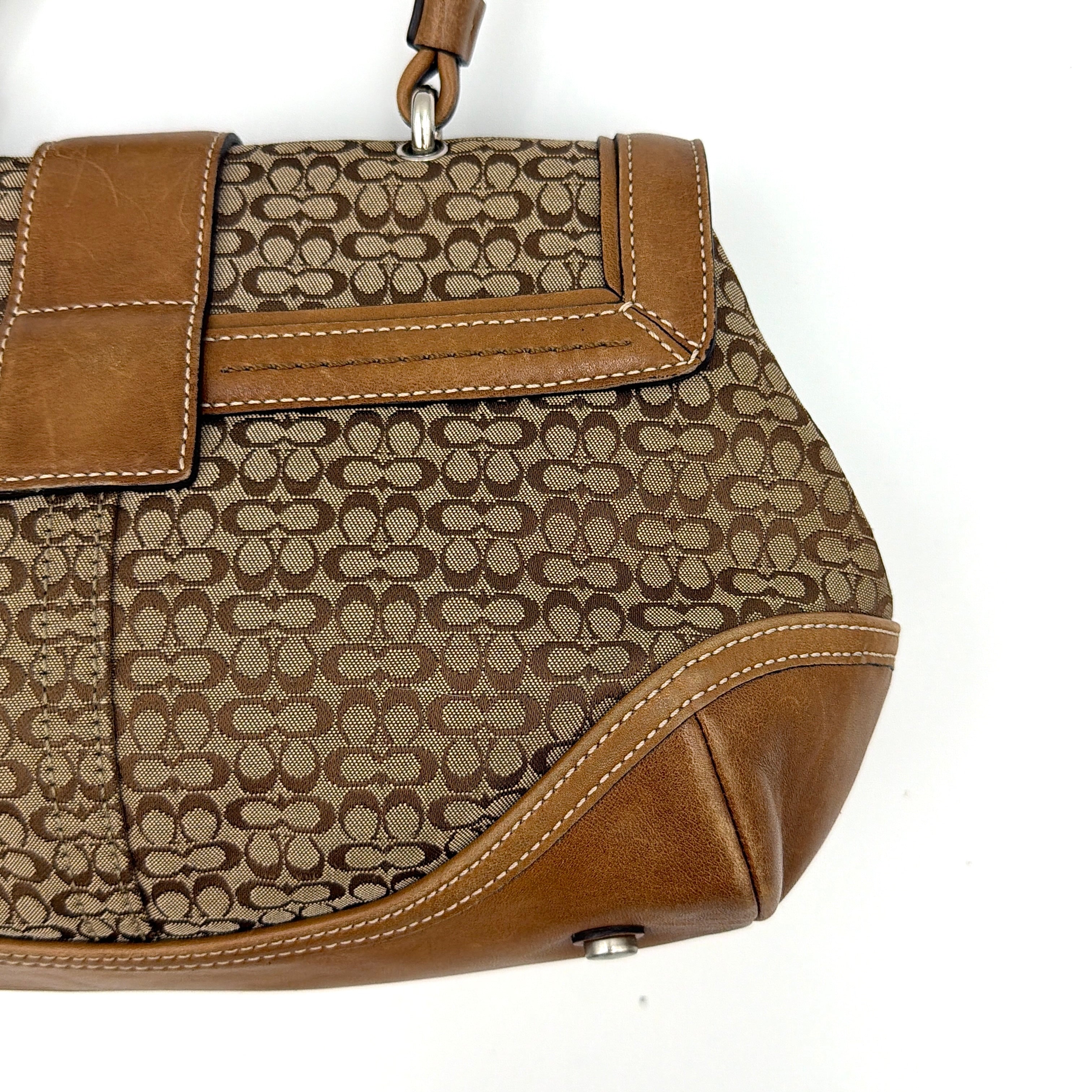 Coach Soho Shoulder Bag in beige and tan monogram jacquard with caramel leather trim, featuring silver hardware and a signature buckle flap.