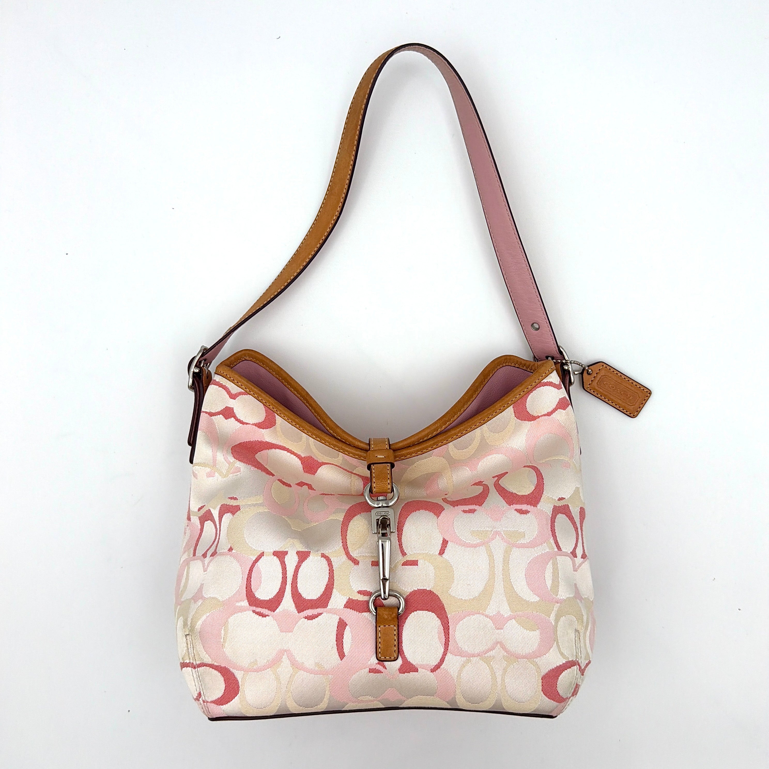 Coach hobo handbag in pink-cream canvas with signature C motif and tan leather trim, featuring a silver clip detail and a structured silhouette.