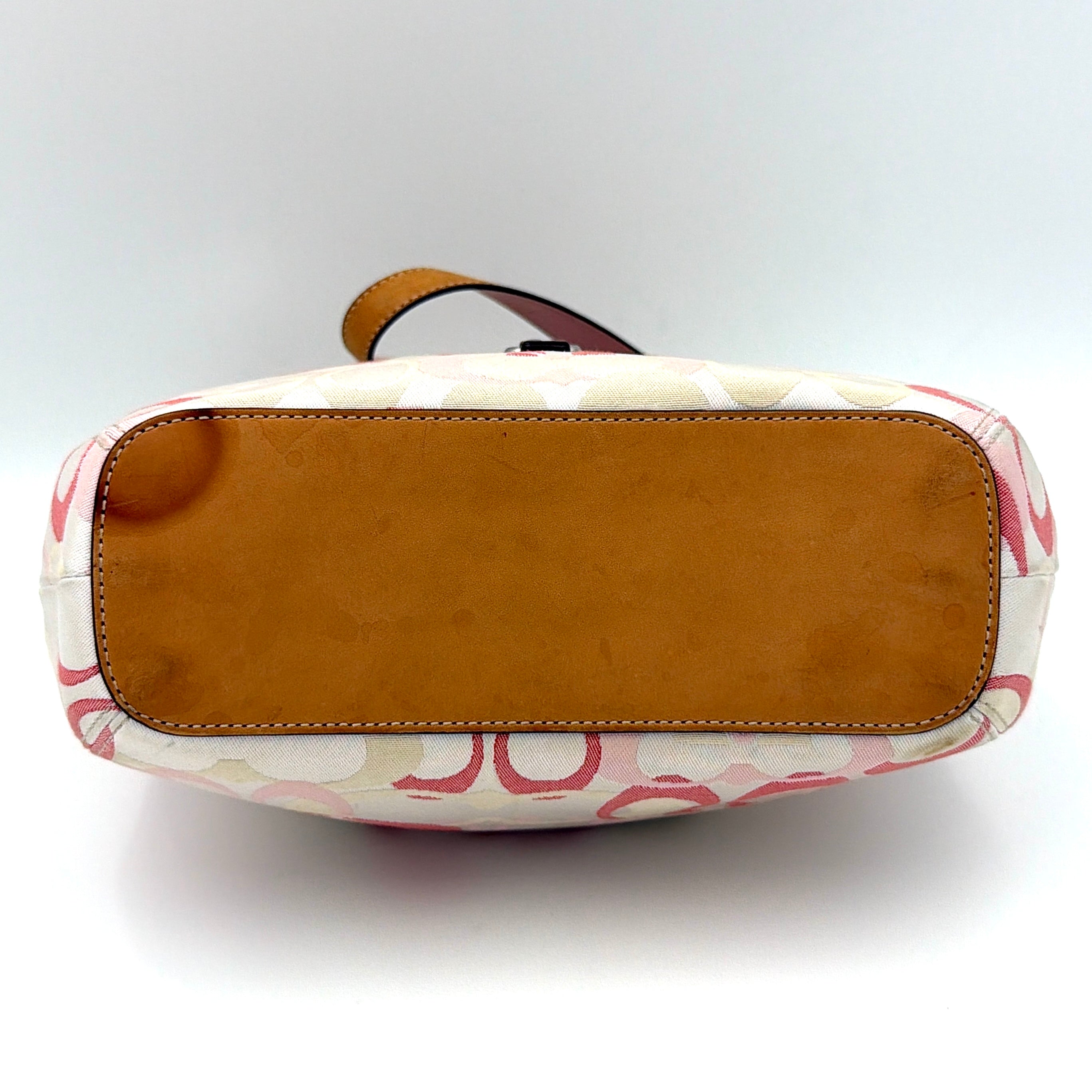 Coach hobo handbag in pink-cream canvas with signature C motif and tan leather trim, featuring a silver clip detail and a structured silhouette.