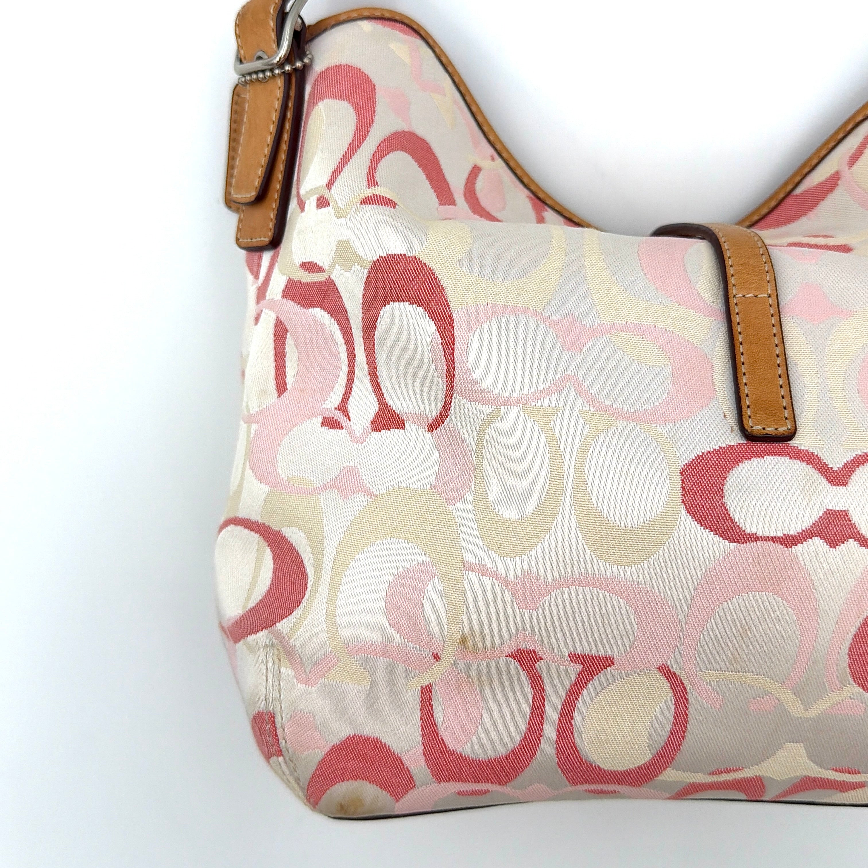 Coach hobo handbag in pink-cream canvas with signature C motif and tan leather trim, featuring a silver clip detail and a structured silhouette.