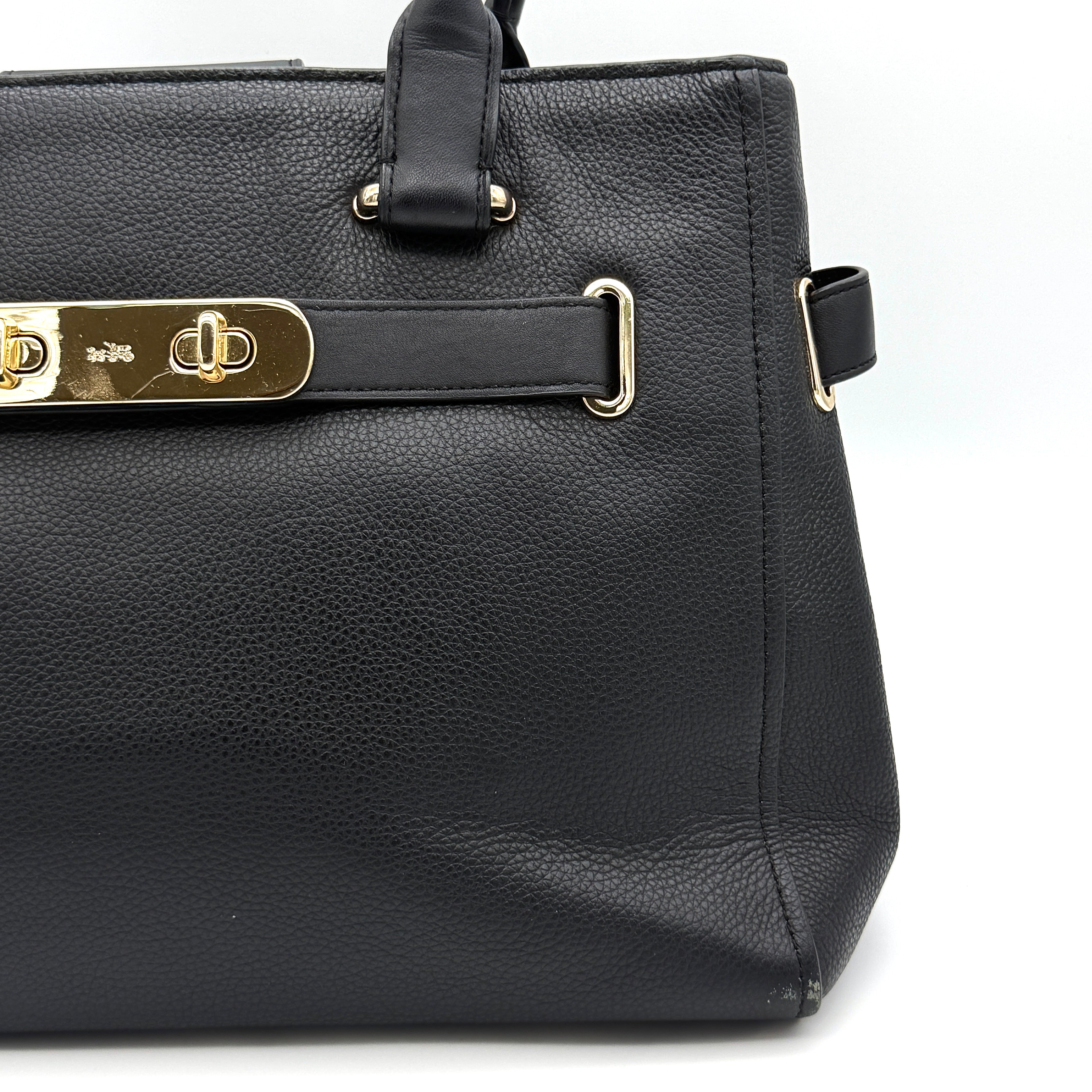 Coach Swagger Carryall in black pebbled leather with gold-tone hardware and double turnlock detail, shown from the front.