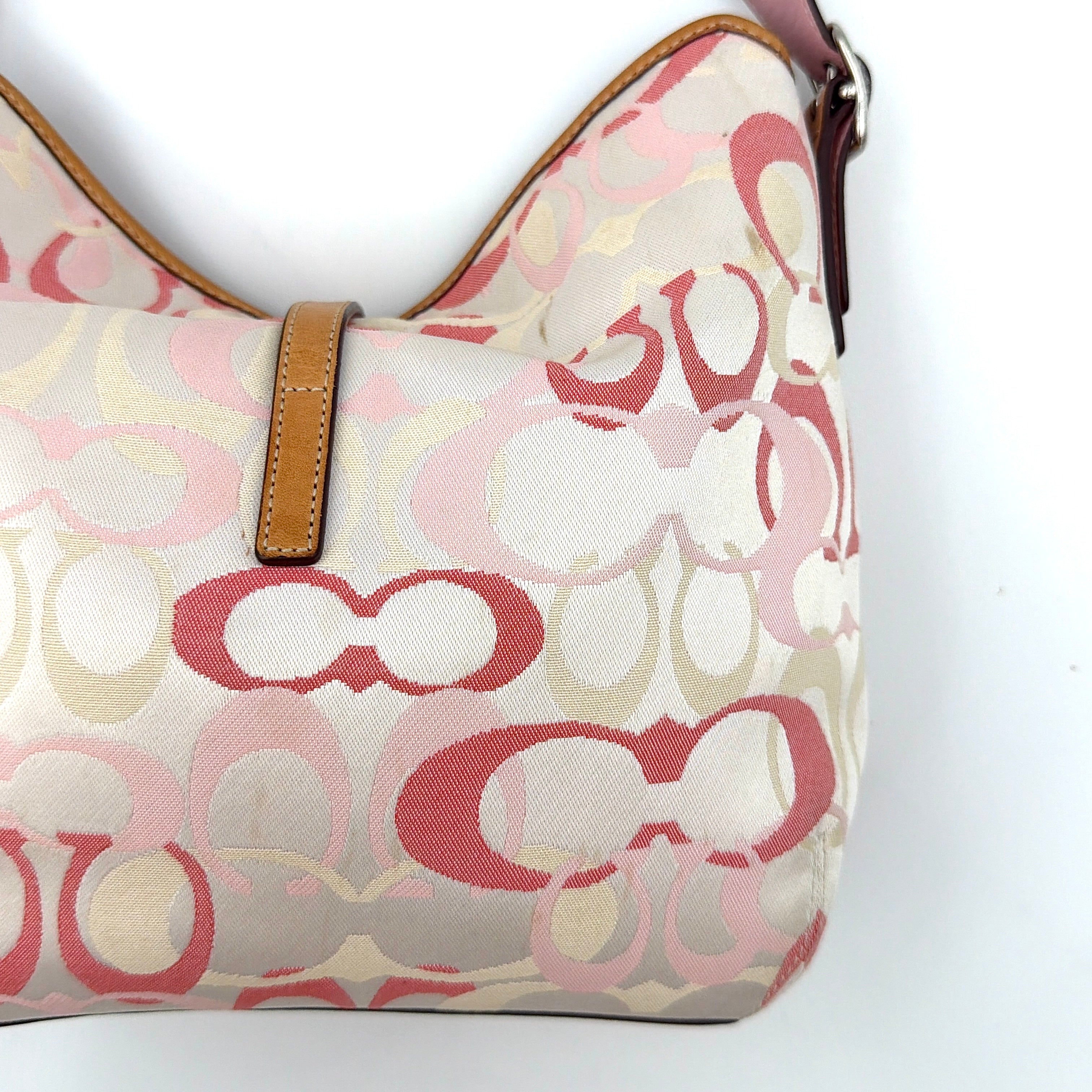 Coach hobo handbag in pink-cream canvas with signature C motif and tan leather trim, featuring a silver clip detail and a structured silhouette.