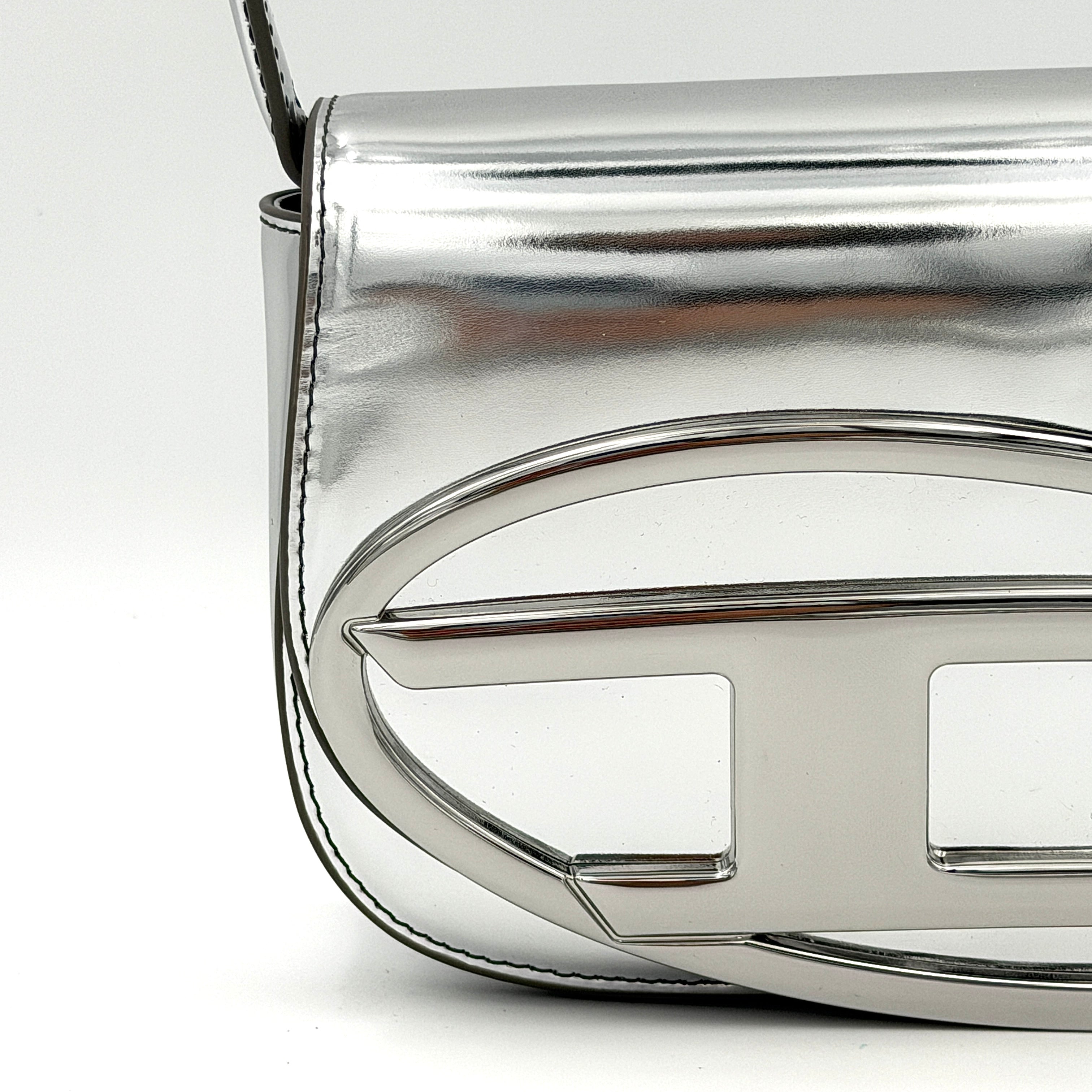 Diesel 1DR 2Way metallic silver shoulder bag with sculptural D logo and detachable strap displayed against a plain background.