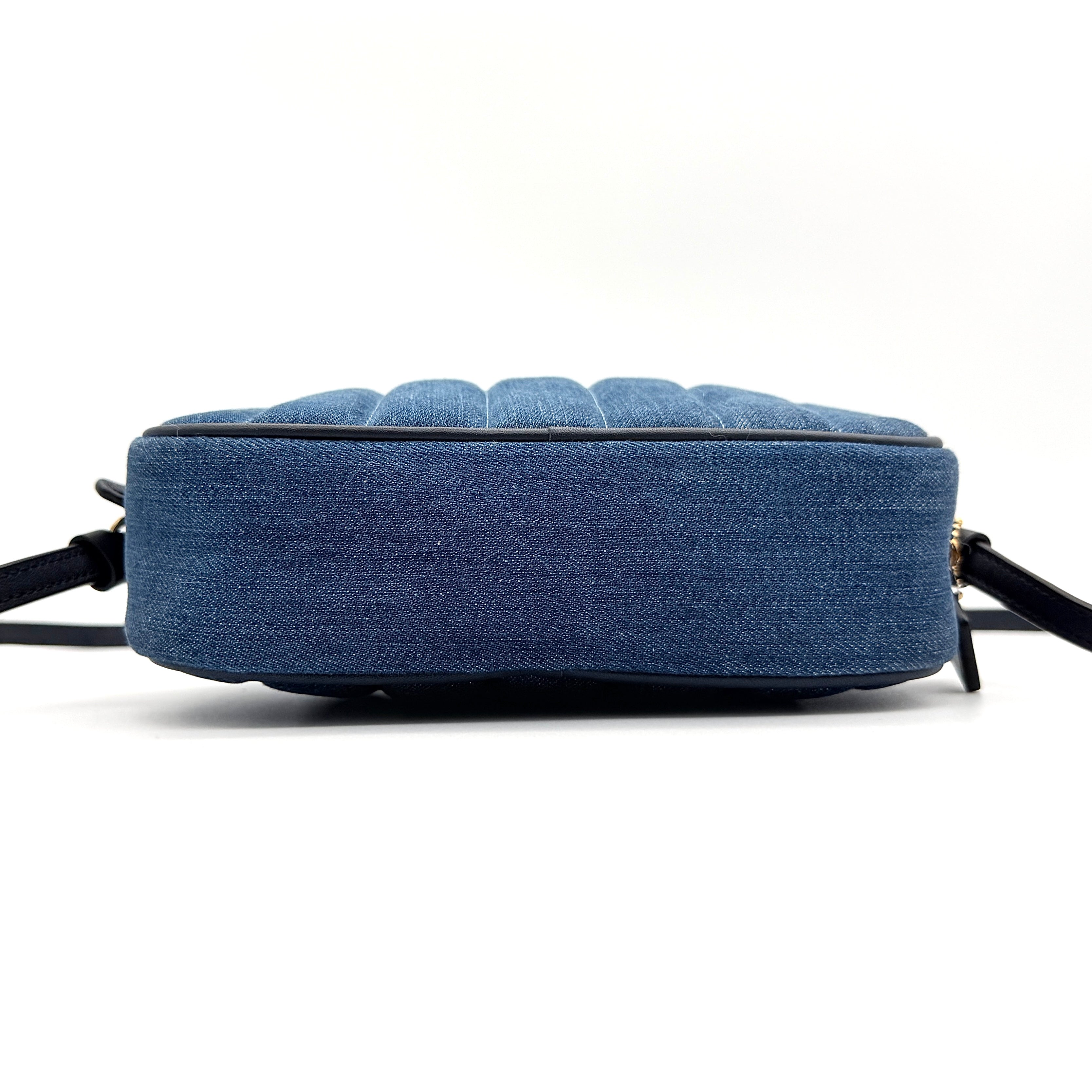 Coach Jamie Mini Camera Bag in quilted blue denim with navy leather trim and gold hardware, shown with its adjustable crossbody strap.