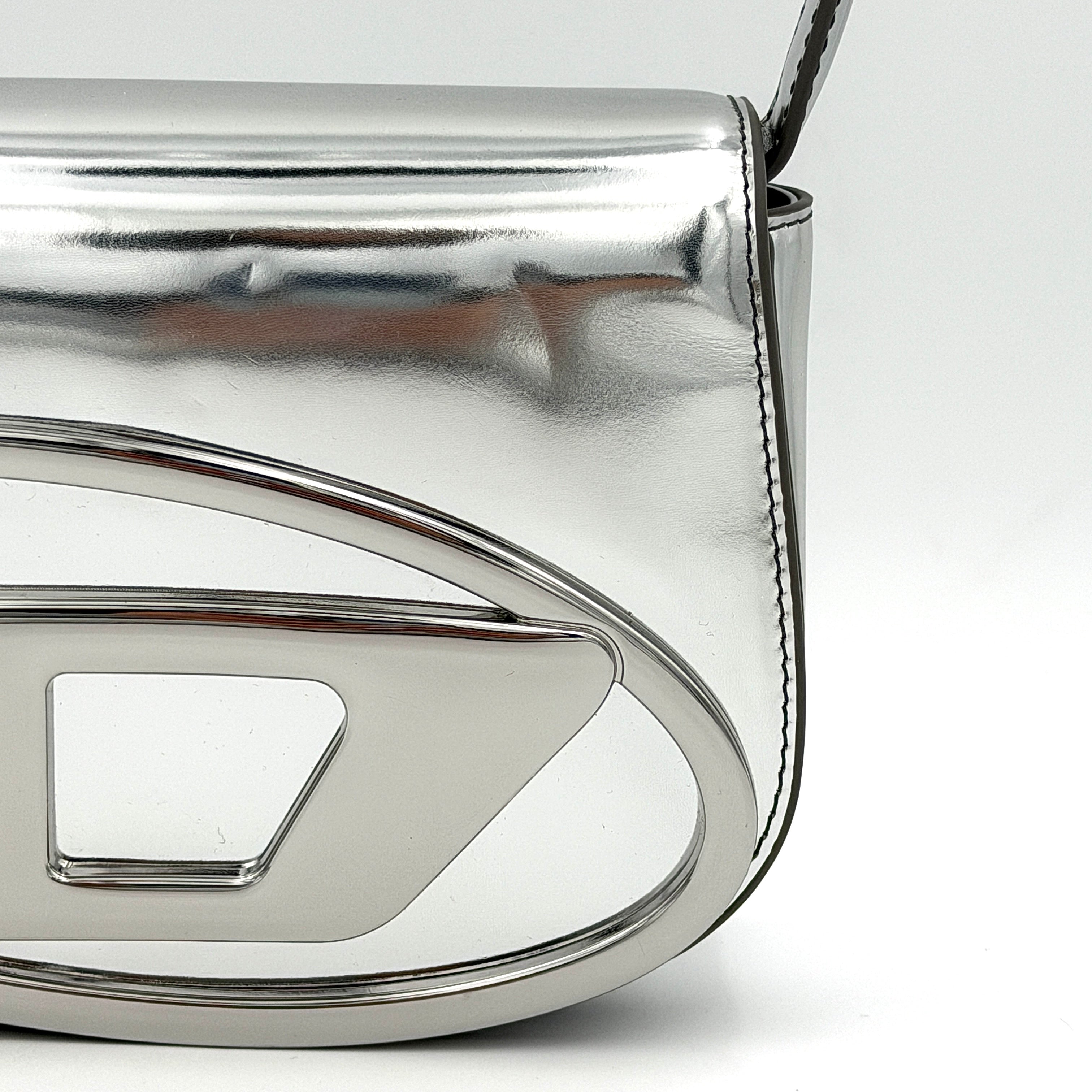Diesel 1DR 2Way metallic silver shoulder bag with sculptural D logo and detachable strap displayed against a plain background.