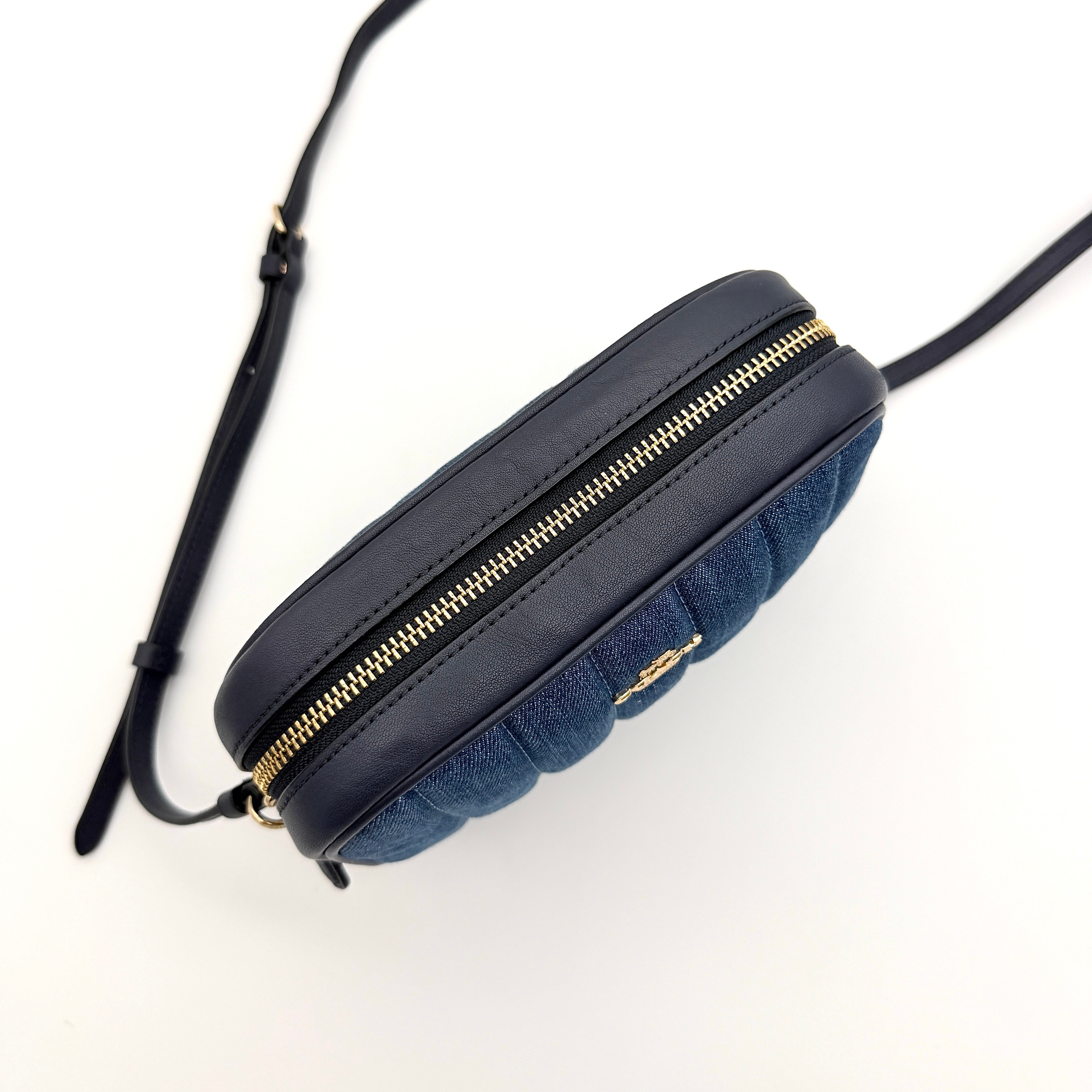 Coach Jamie Mini Camera Bag in quilted blue denim with navy leather trim and gold hardware, shown with its adjustable crossbody strap.