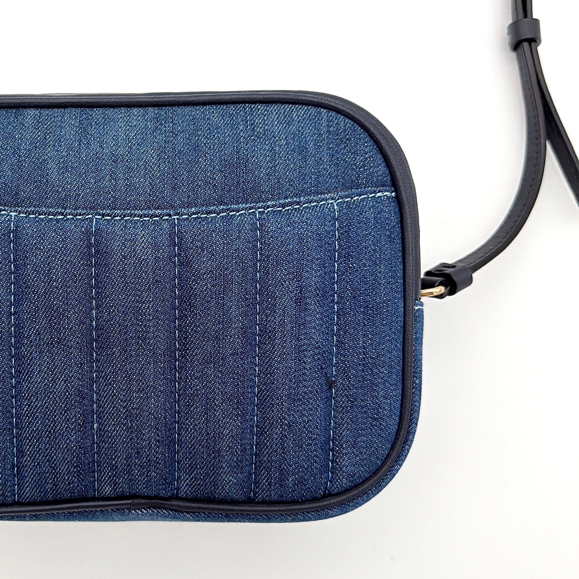 Coach Jamie Mini Camera Bag in quilted blue denim with navy leather trim and gold hardware, shown with its adjustable crossbody strap.