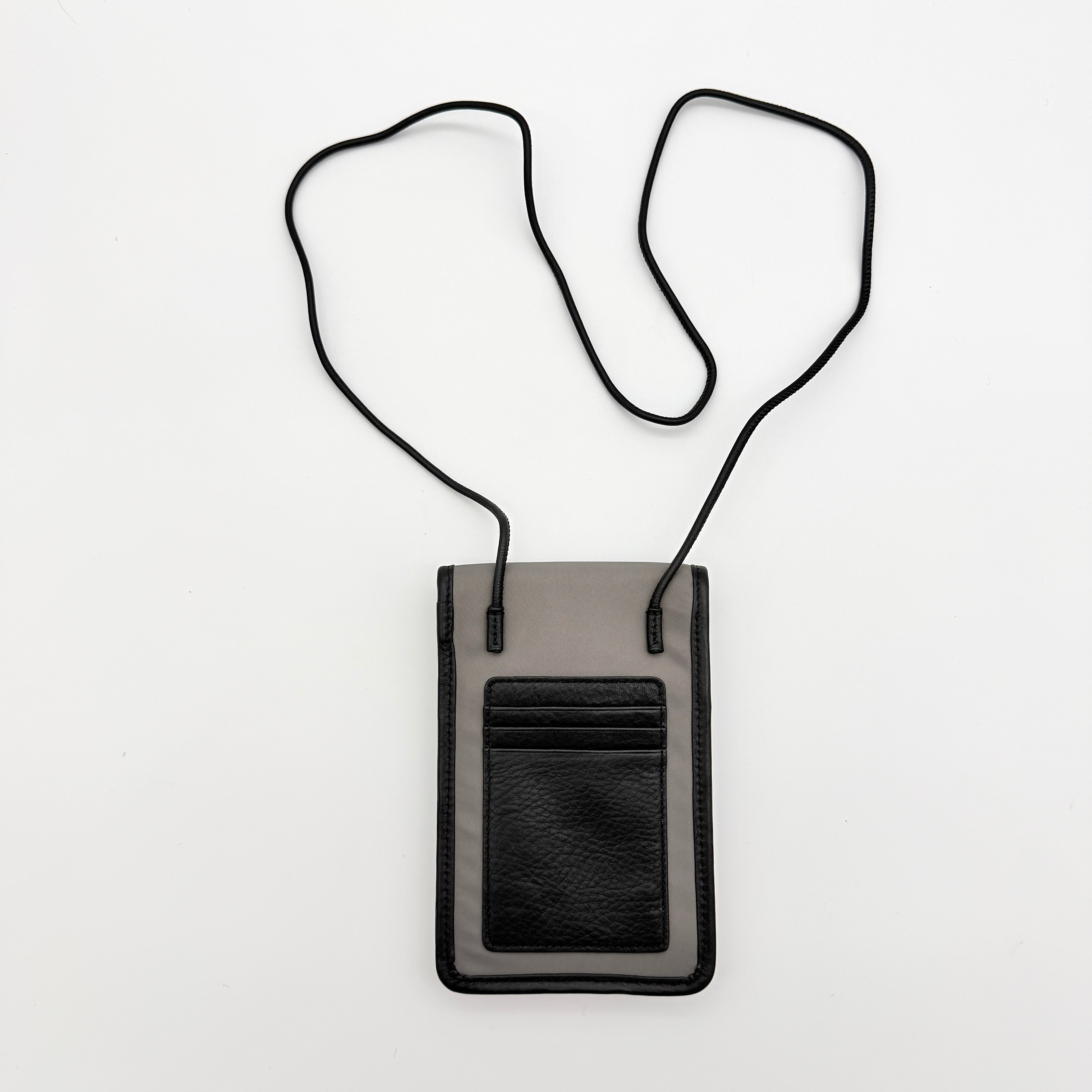 Furla Cosmo grey phone holder with black trim, silver buckle, and black cord strap on white background.