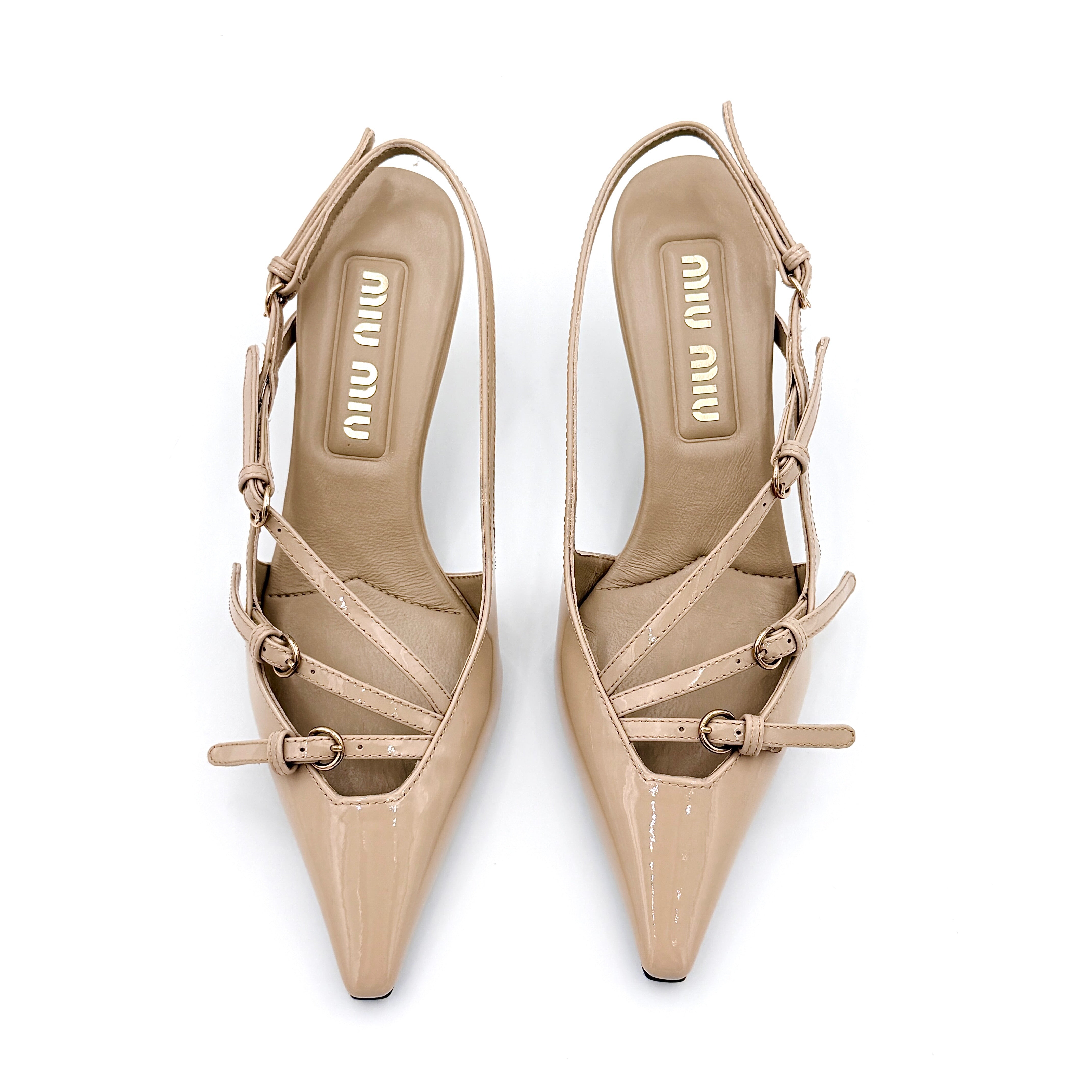 A pair of Miu Miu beige patent leather slingback pumps with pointed toes and gold-tone buckles displayed on a white background.