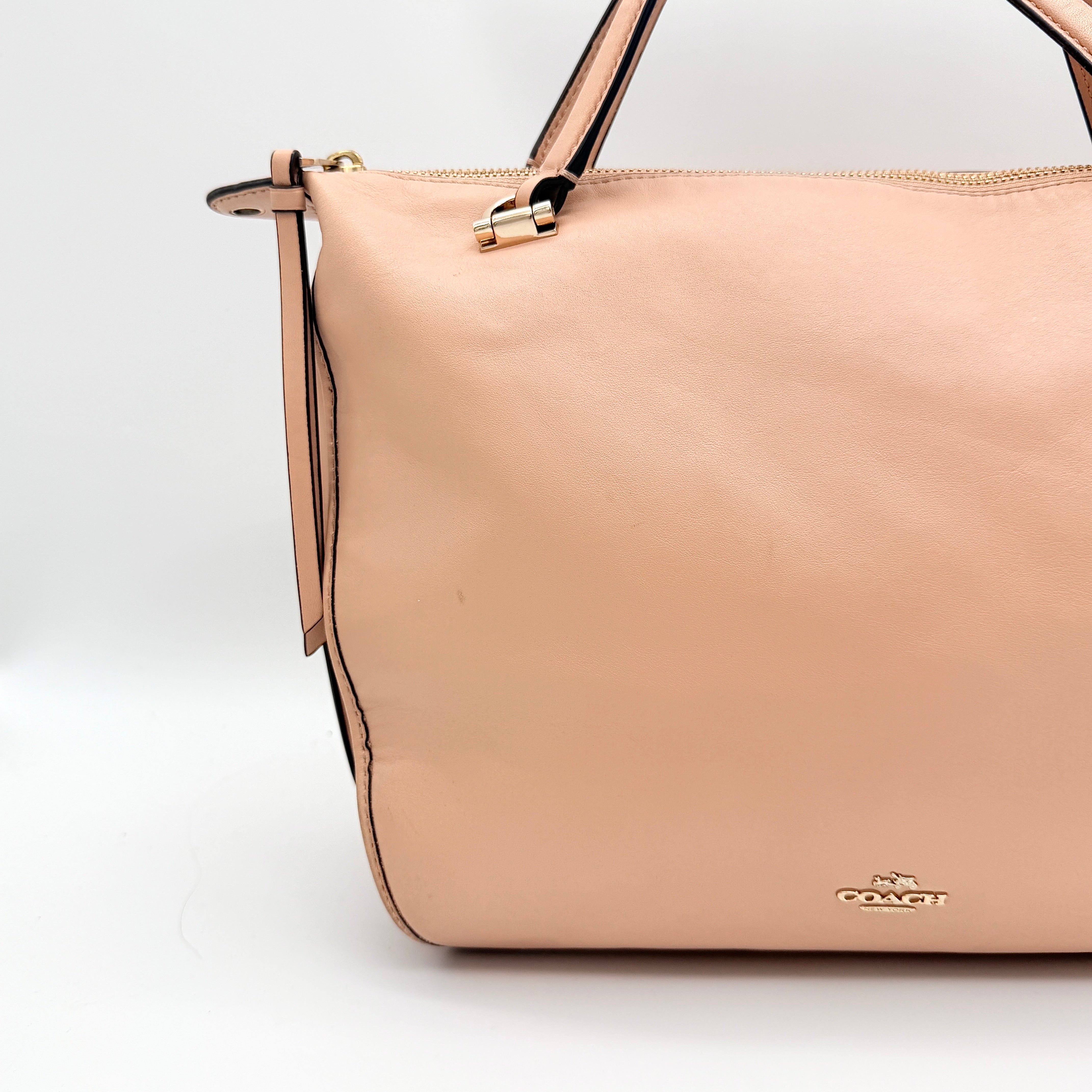 Coach Madison Smythe satchel in blush pink leather with gold-tone hardware and detachable strap, displayed against a white background.