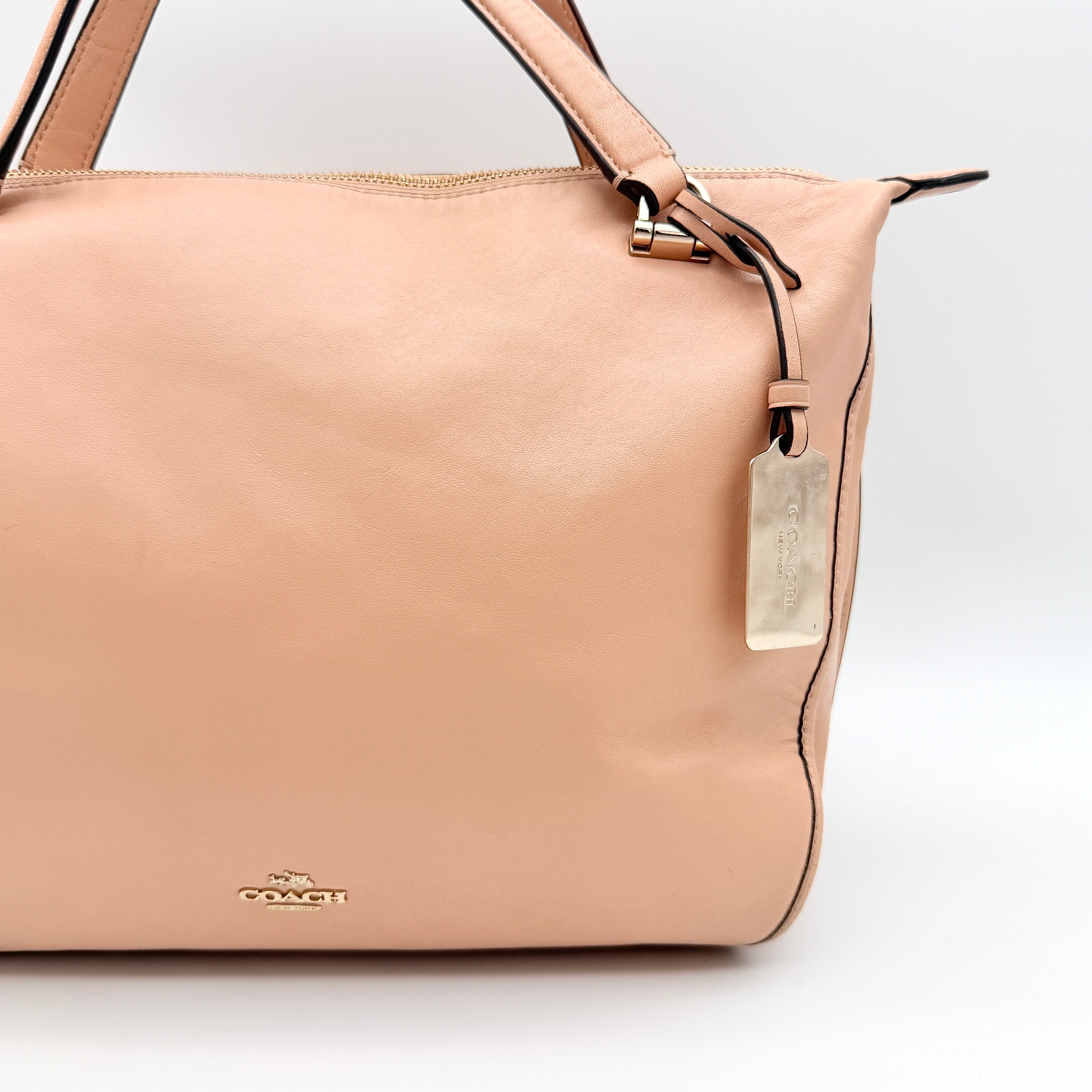 Coach Madison Smythe satchel in blush pink leather with gold-tone hardware and detachable strap, displayed against a white background.