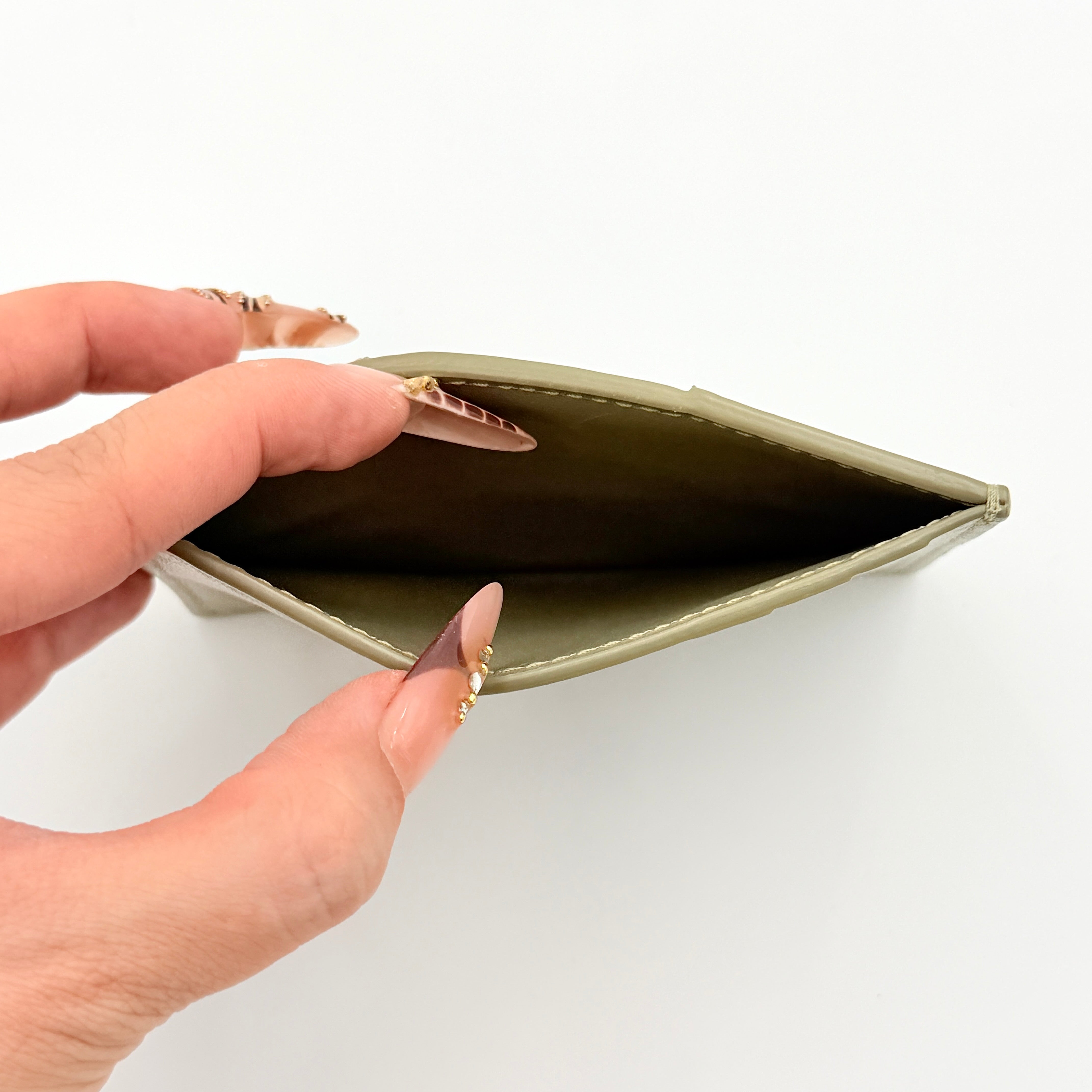 Bottega Veneta Cassette card holder in travertine green leather with signature padded Intrecciato weave, photographed against a white background.