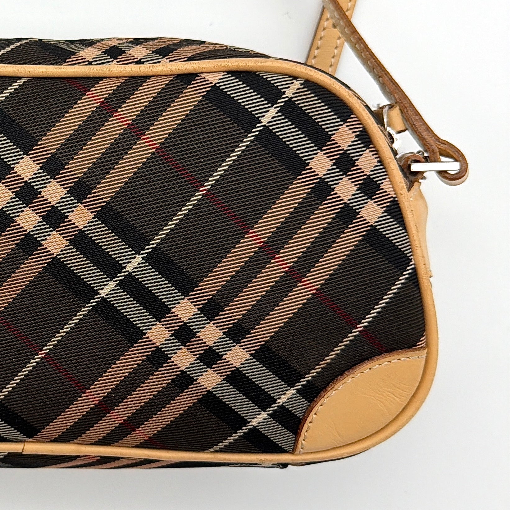 Burberry Blue Label Nova Check crossbody bag with tan leather trim and heart charm, styled on a white background.