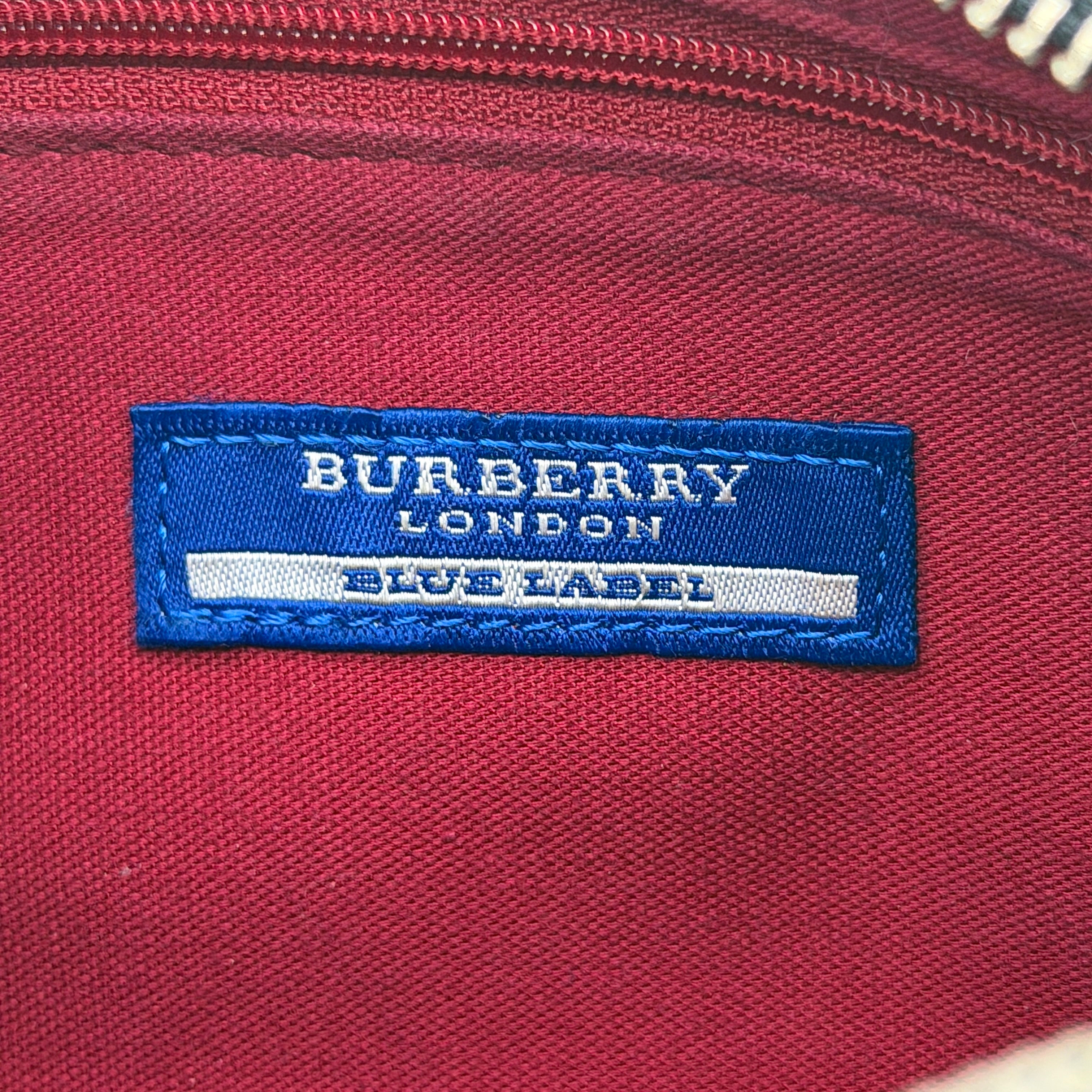 Burberry Blue Label Nova Check crossbody bag with tan leather trim and heart charm, styled on a white background.