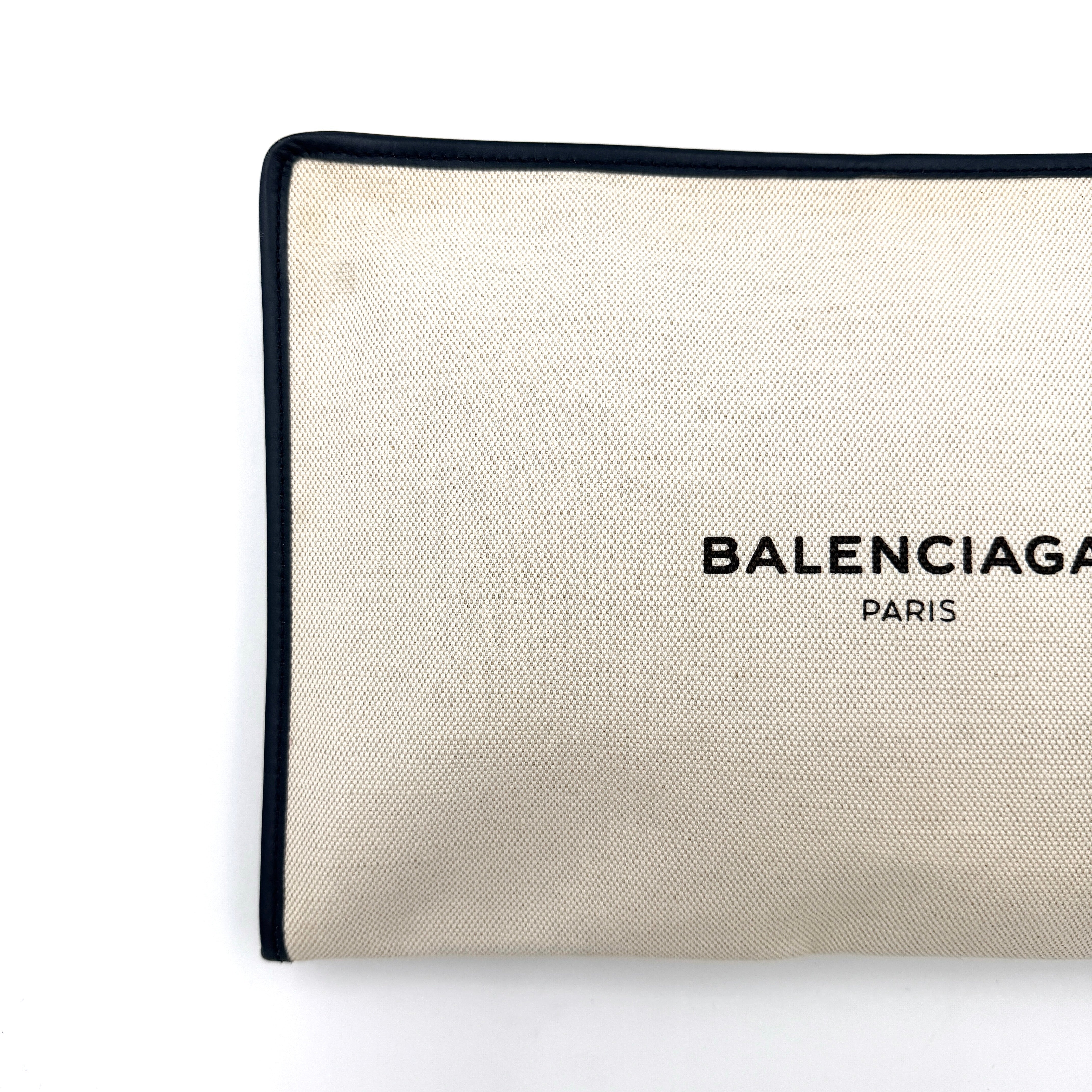 Balenciaga large ivory canvas clutch with black leather trim and logo, shown against a plain background.