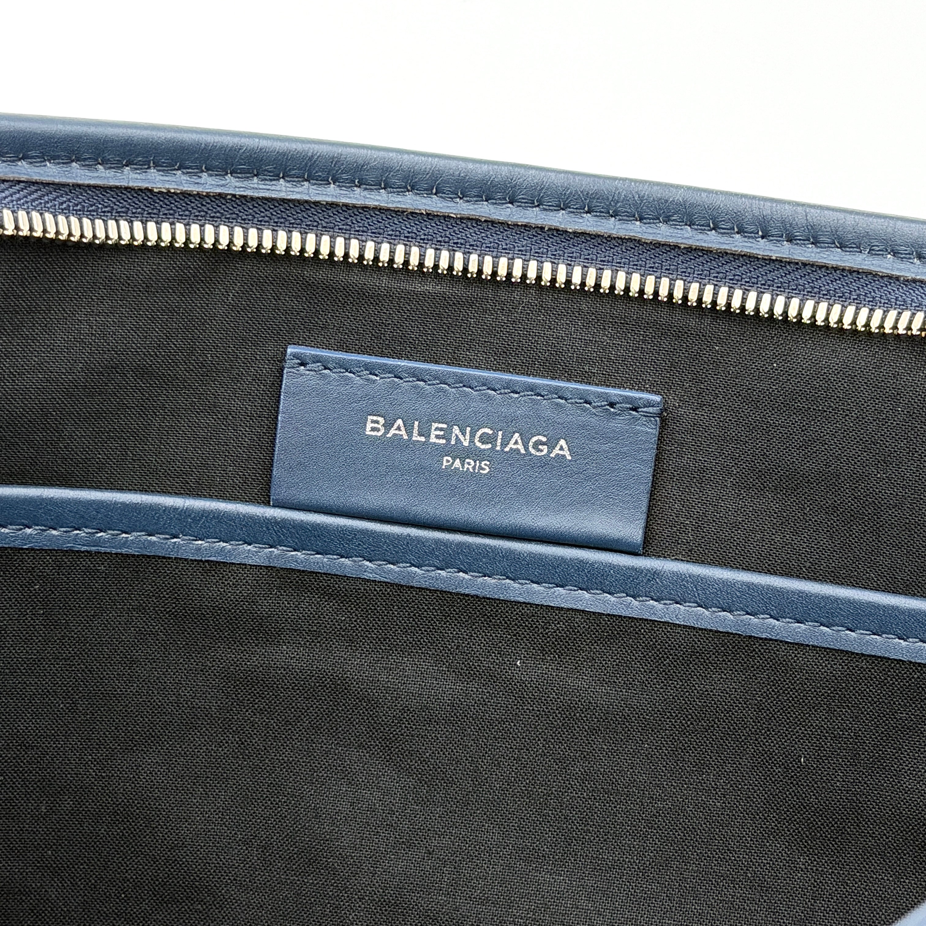Balenciaga large ivory canvas clutch with black leather trim and logo, shown against a plain background.