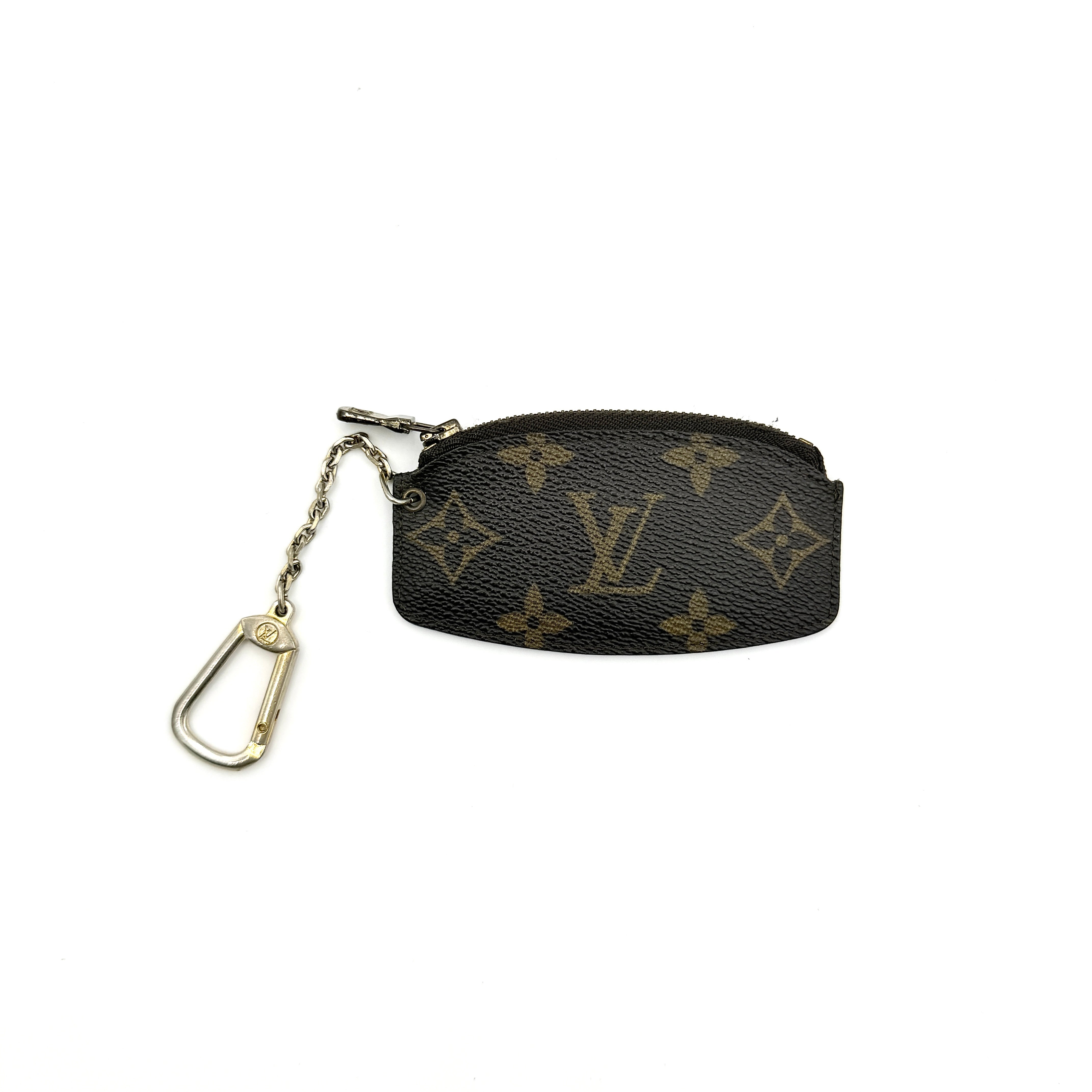 Louis Vuitton Monogram Cles coin case in brown canvas with gold-tone chain and clasp, photographed against a white background.