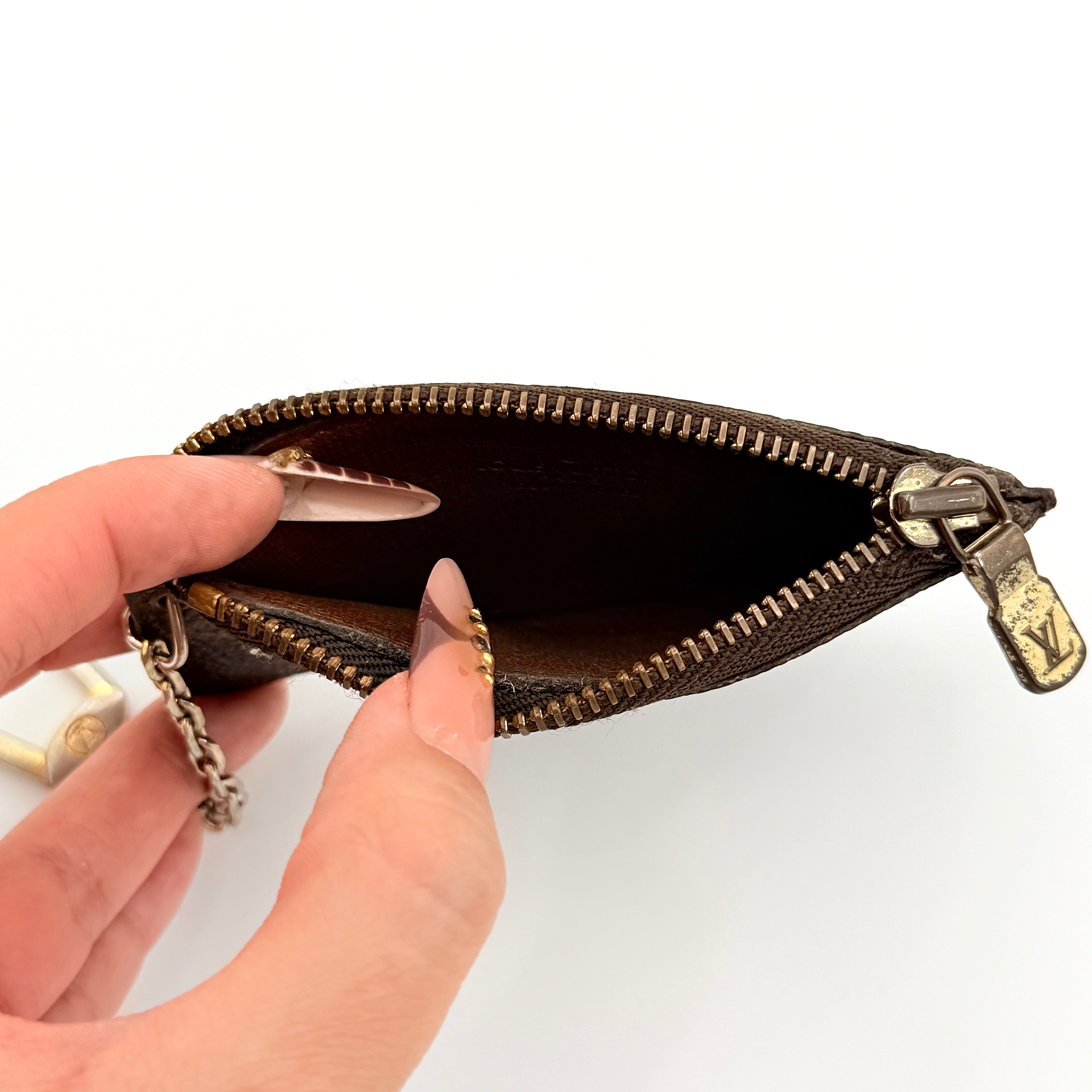 Louis Vuitton Monogram Cles coin case in brown canvas with gold-tone chain and clasp, photographed against a white background.