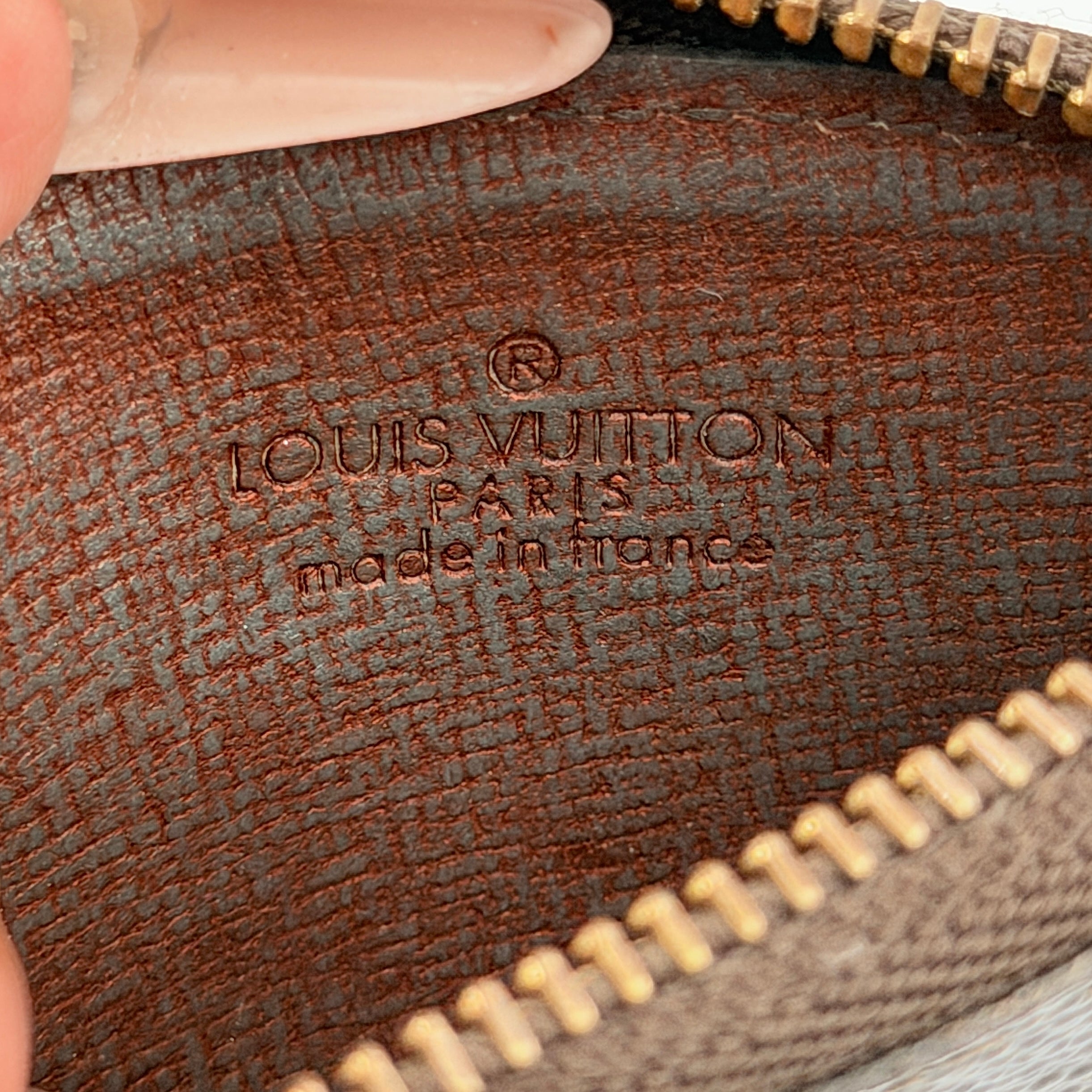 Louis Vuitton Monogram Cles coin case in brown canvas with gold-tone chain and clasp, photographed against a white background.
