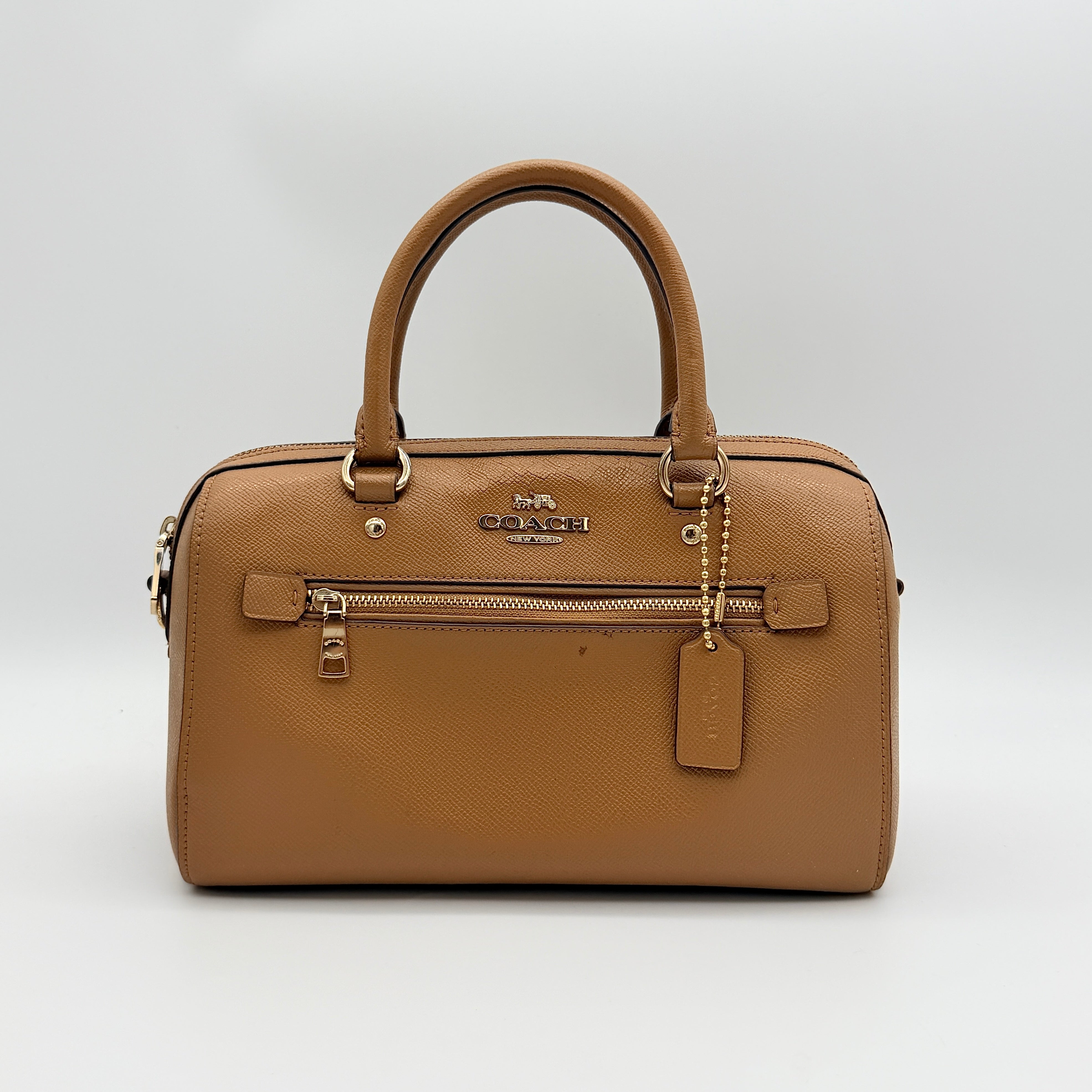 Coach Rowan satchel in brown grained leather with gold hardware, shown with dust bag, strap, and care cards.