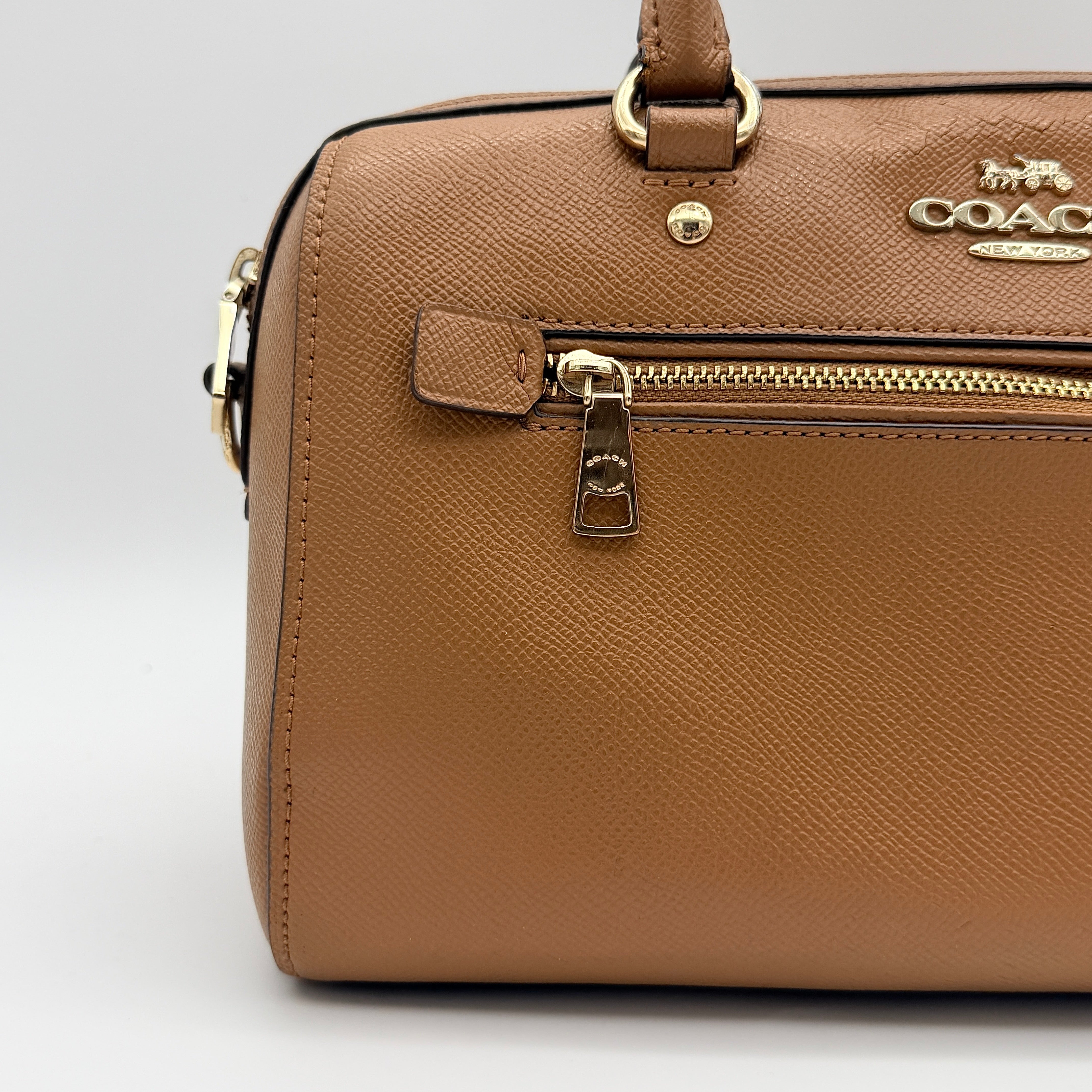Coach Rowan satchel in brown grained leather with gold hardware, shown with dust bag, strap, and care cards.