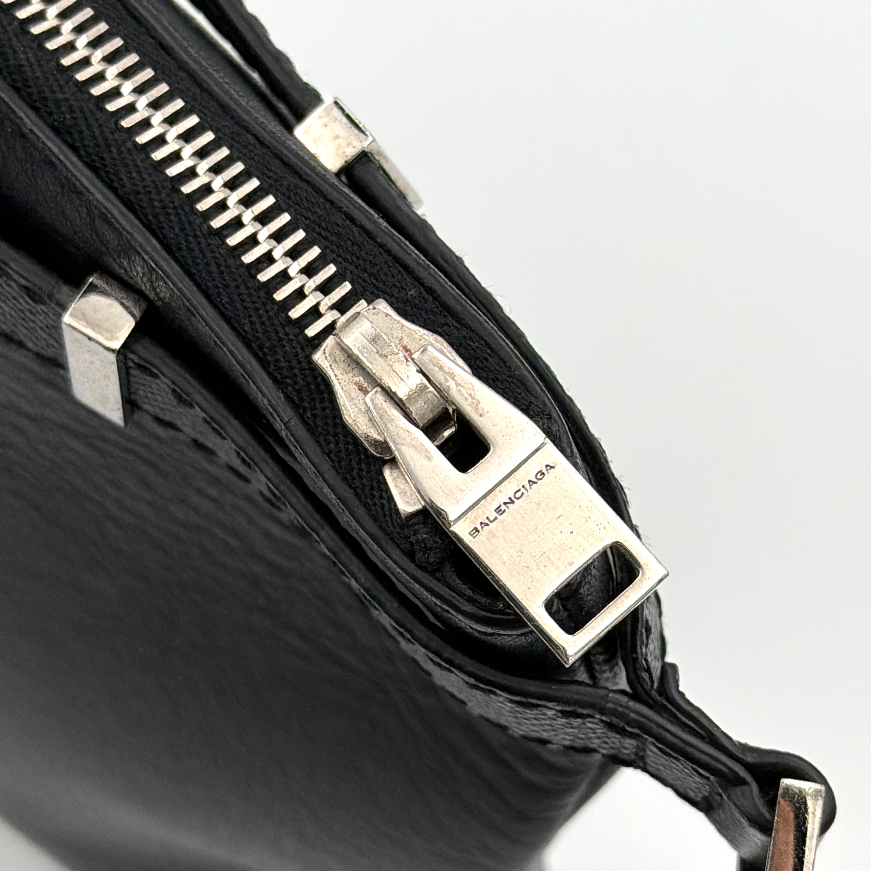 Balenciaga Phileas clutch in smooth black leather with silver hardware, shown against a white background.
