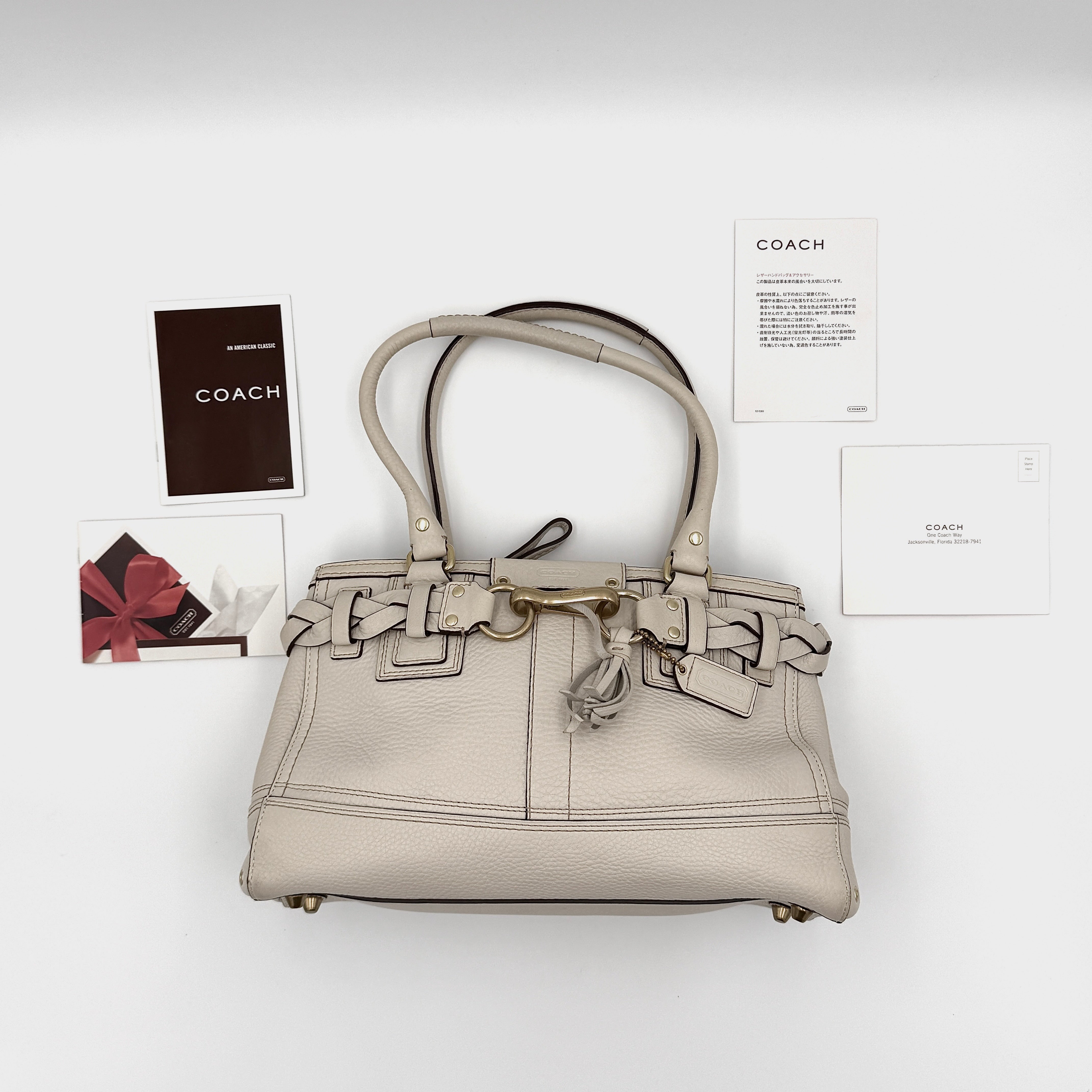 Coach Signature Hampton Carryall Shoulder Bag in ivory pebbled leather with gold-tone hardware and braided detailing, shown from the front.