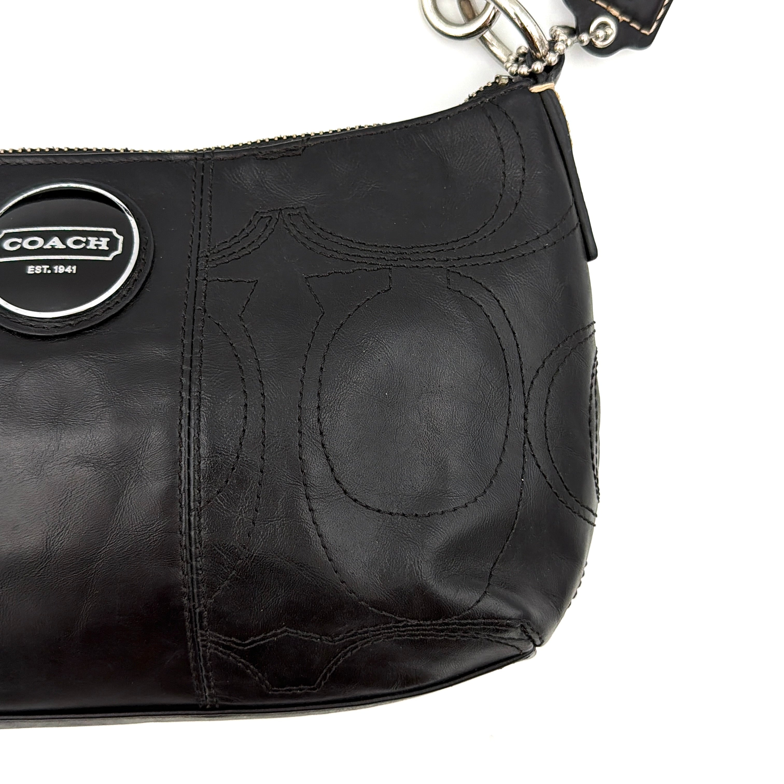 Coach black leather shoulder bag with signature embossed pattern and silver hardware, shown with attached logo tag and short leather strap.