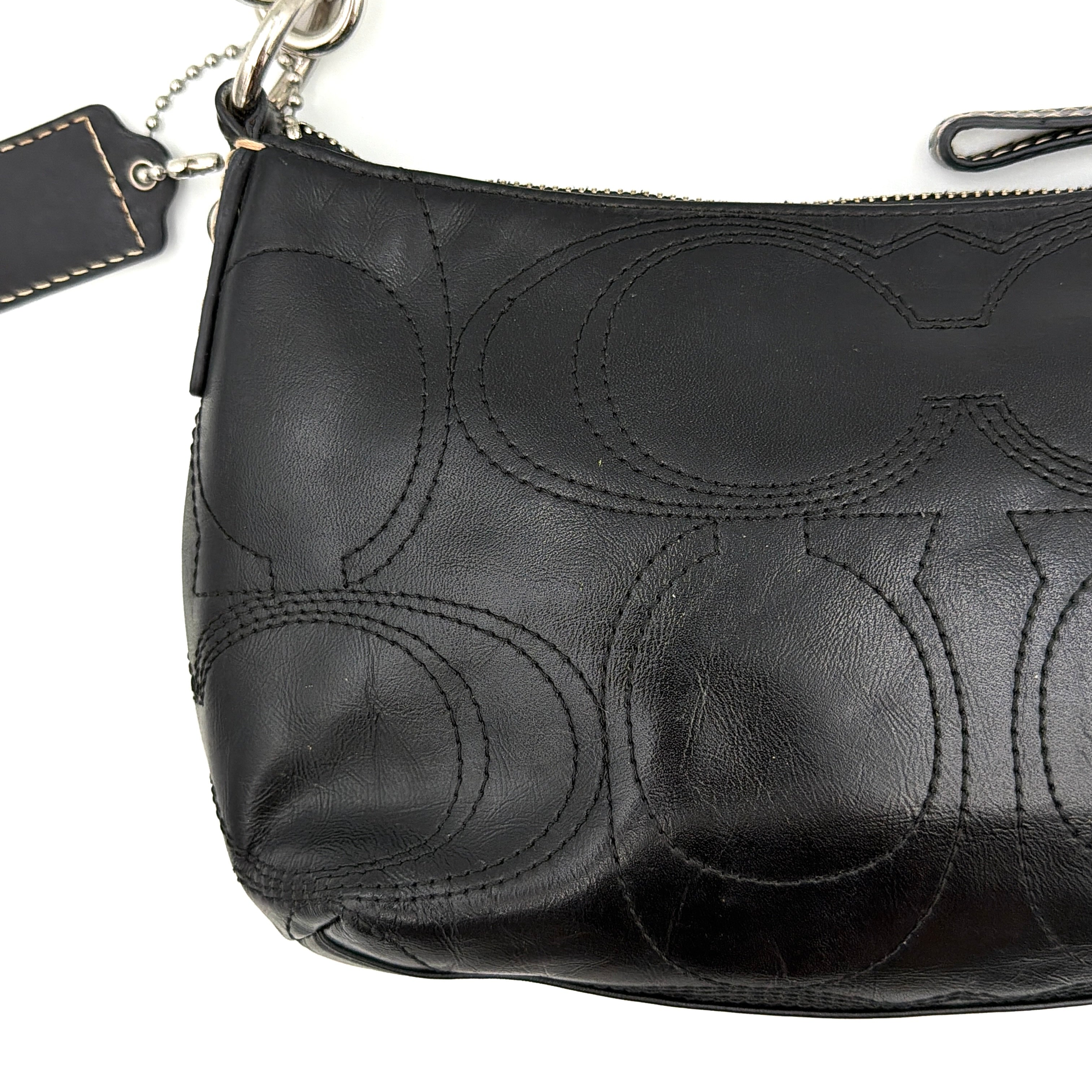 Coach black leather shoulder bag with signature embossed pattern and silver hardware, shown with attached logo tag and short leather strap.