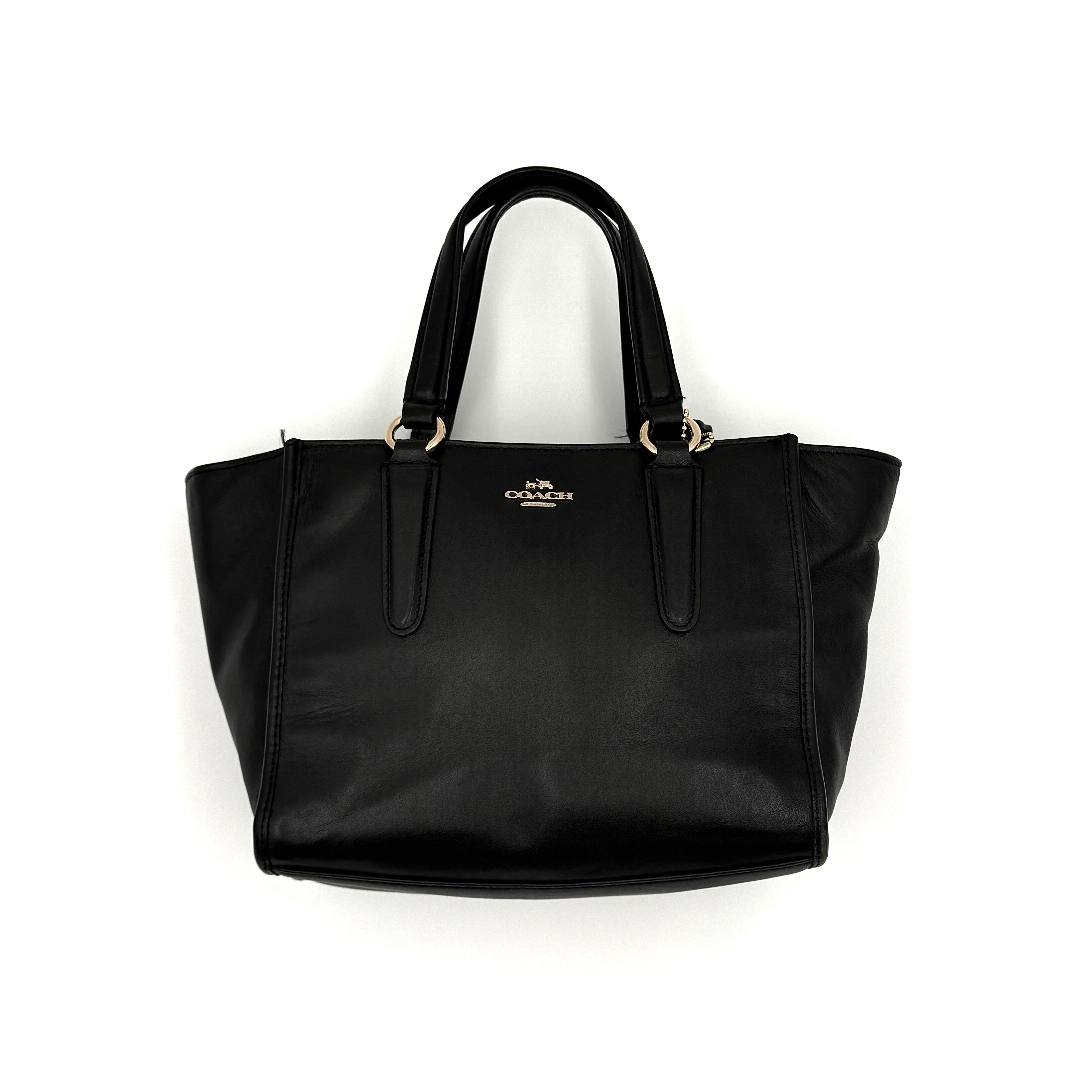 The Coach 2Way Mini Crosby Carryall Handbag in smooth black leather with gold-tone hardware, top handles, and detachable strap displayed alongside.