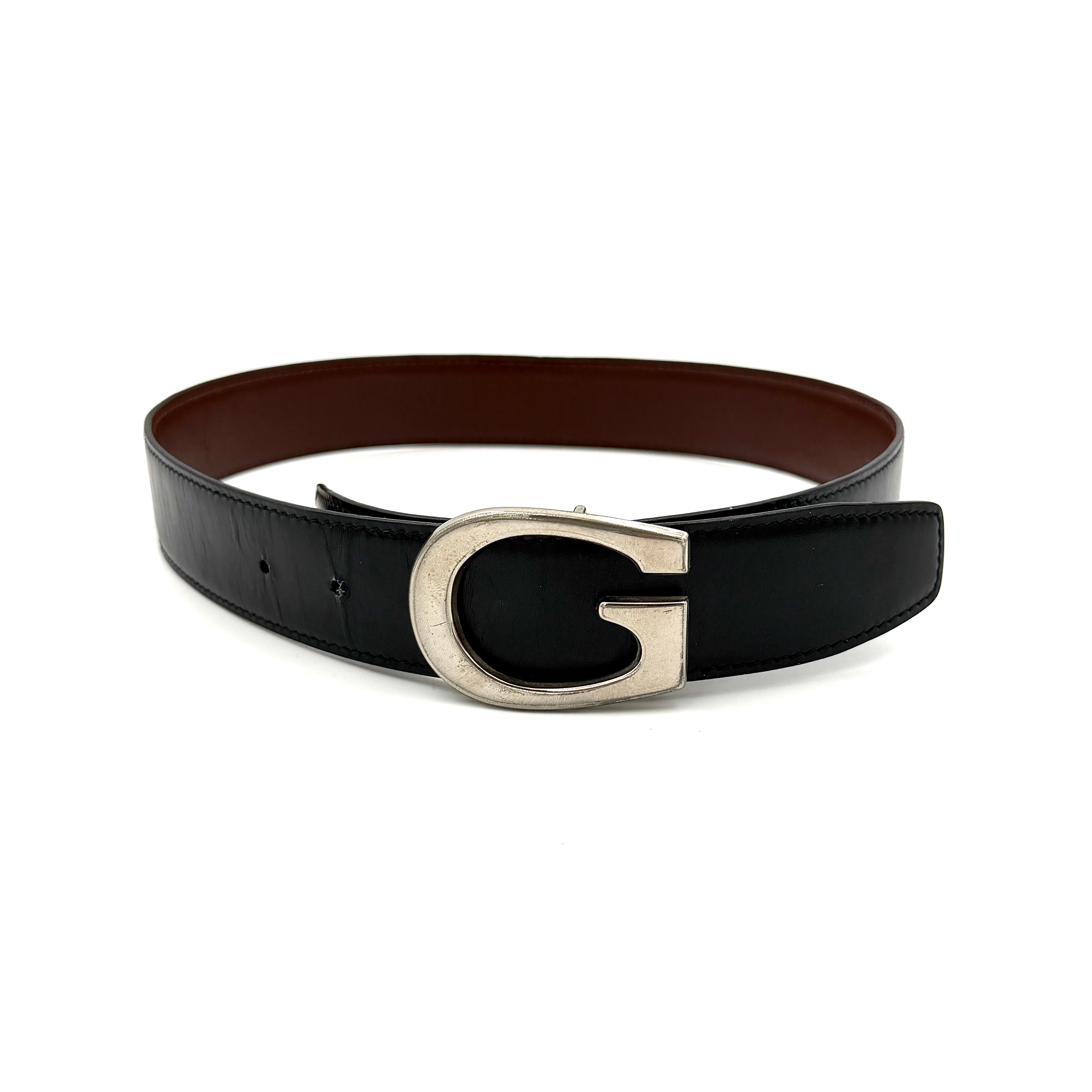 Gucci black leather belt with an oversized silver metal G logo buckle displayed in a curved profile.