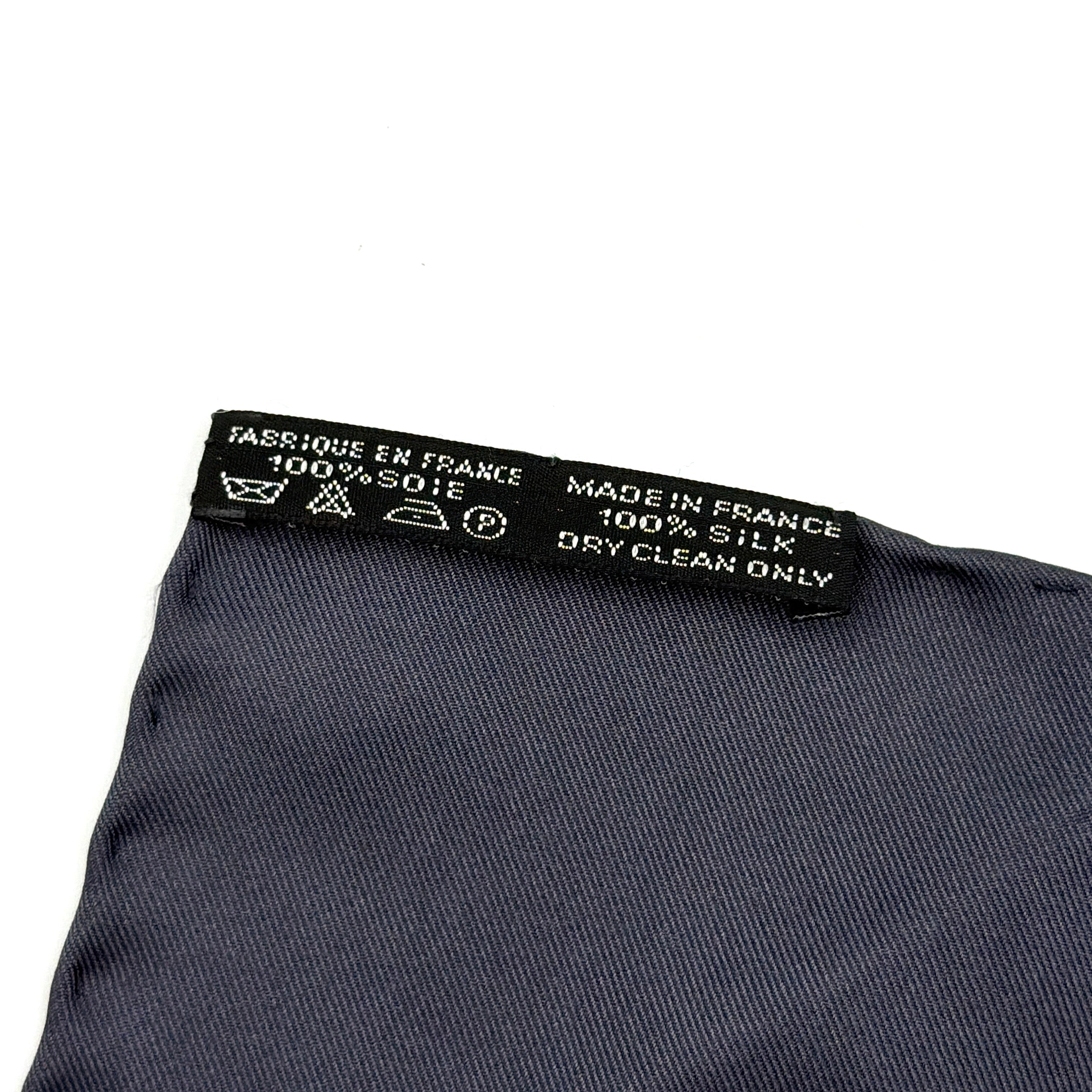 Hermès silk scarf in navy blue with a white chain link pattern and bold border, elegantly displayed flat.