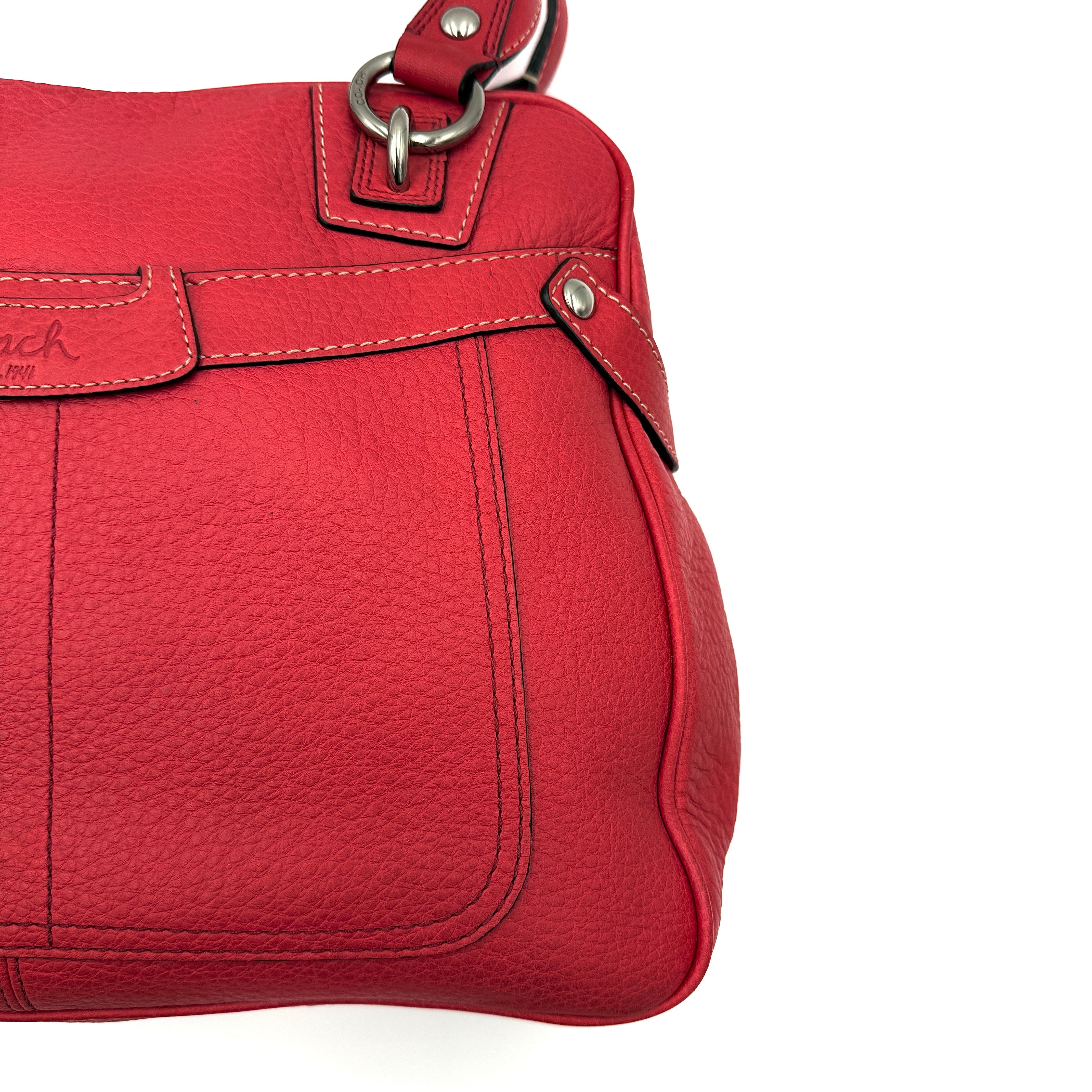 Coach red pebbled leather satchel with dual rolled handles, silver hardware, and structured silhouette.