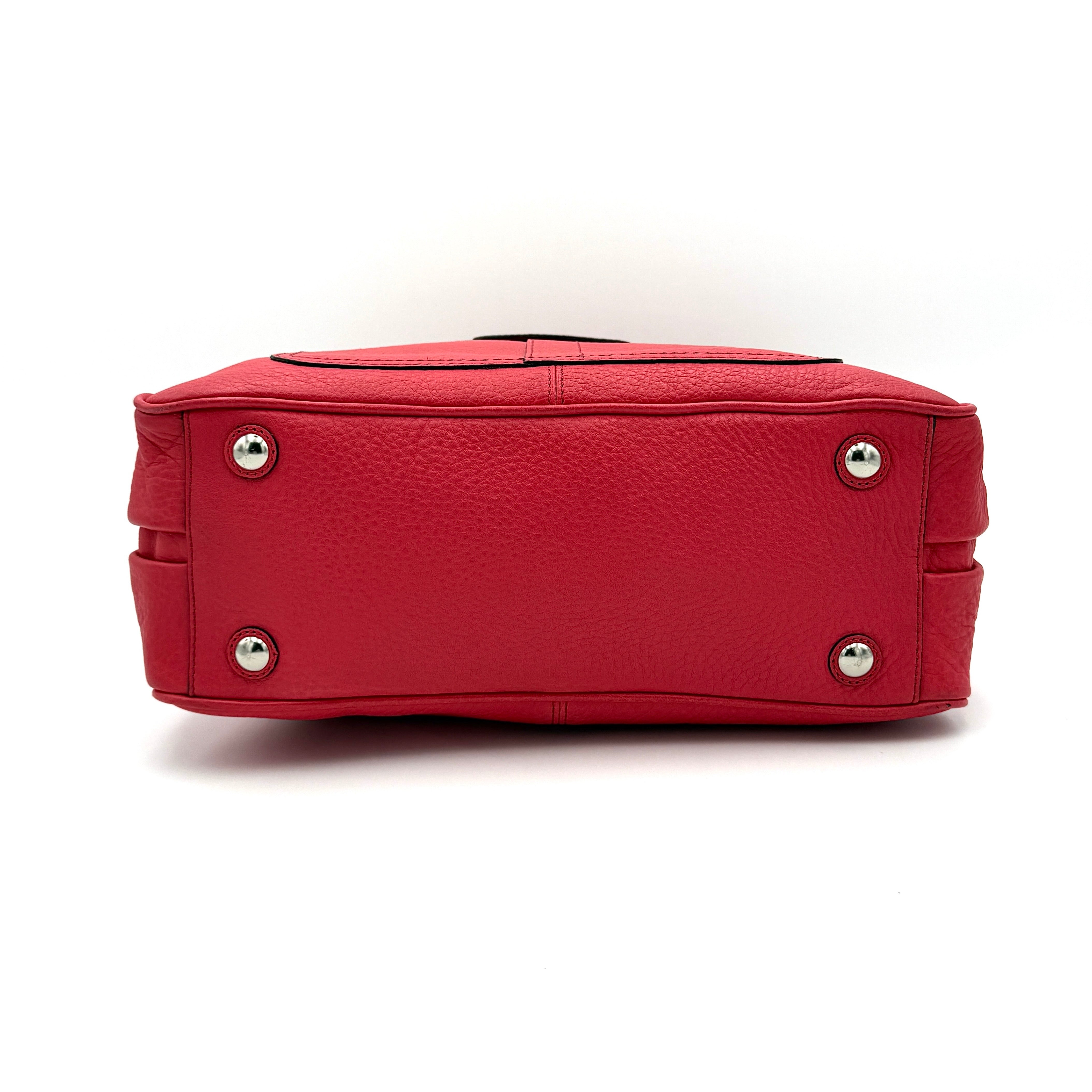 Coach red pebbled leather satchel with dual rolled handles, silver hardware, and structured silhouette.
