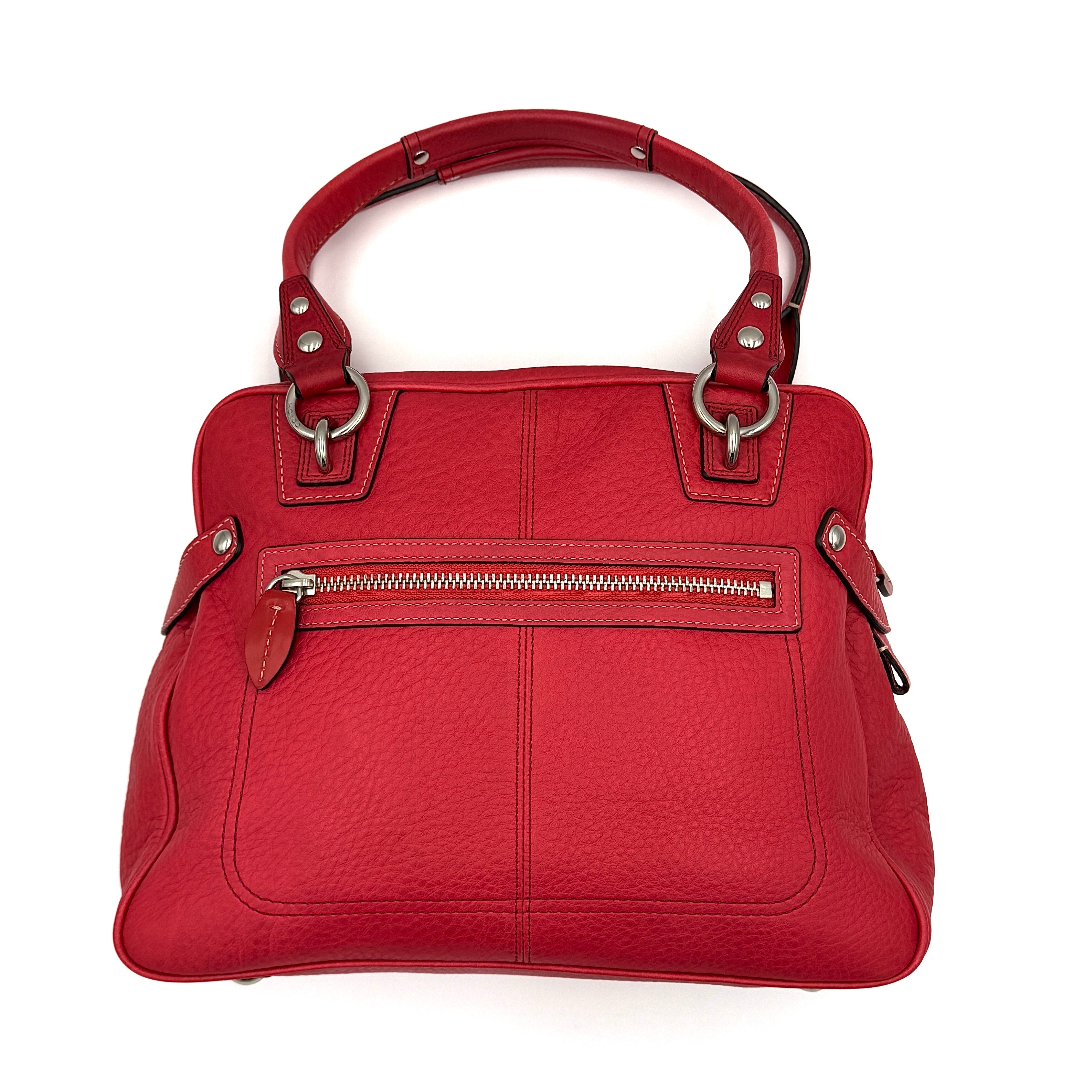 Coach red pebbled leather satchel with dual rolled handles, silver hardware, and structured silhouette.