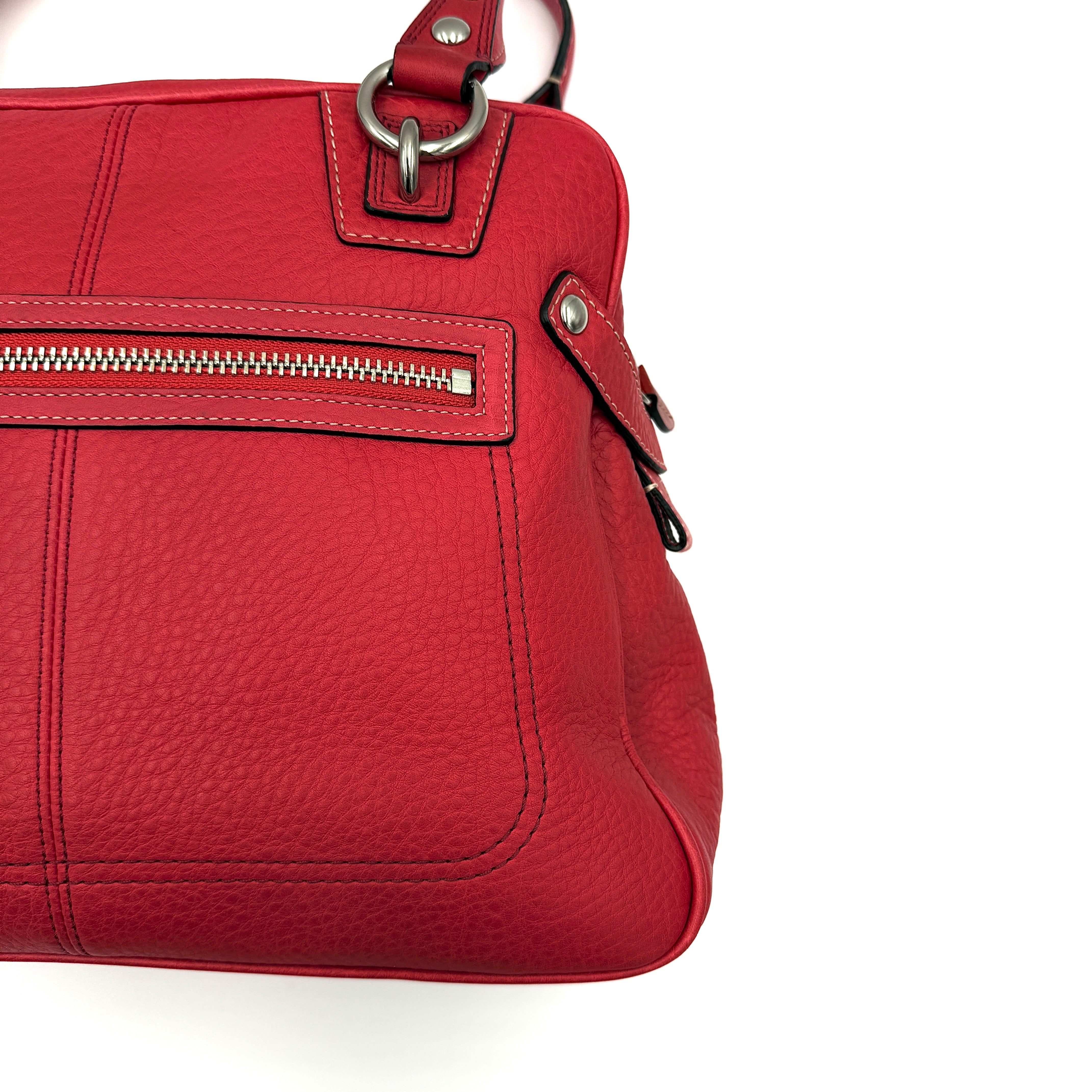 Coach red pebbled leather satchel with dual rolled handles, silver hardware, and structured silhouette.