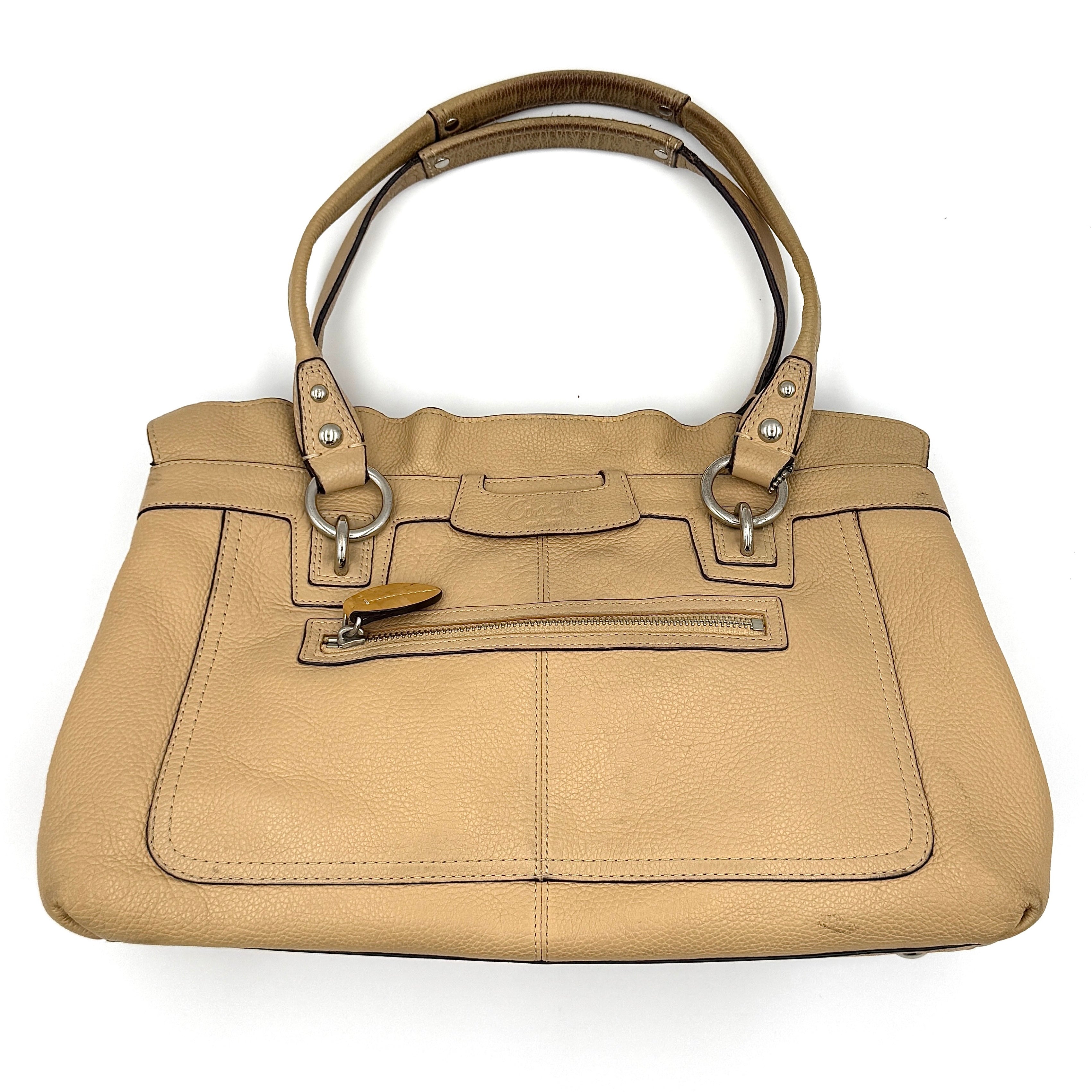 Coach Penelope handbag in cream pebble leather with rolled handles and silver-tone hardware against a white background.