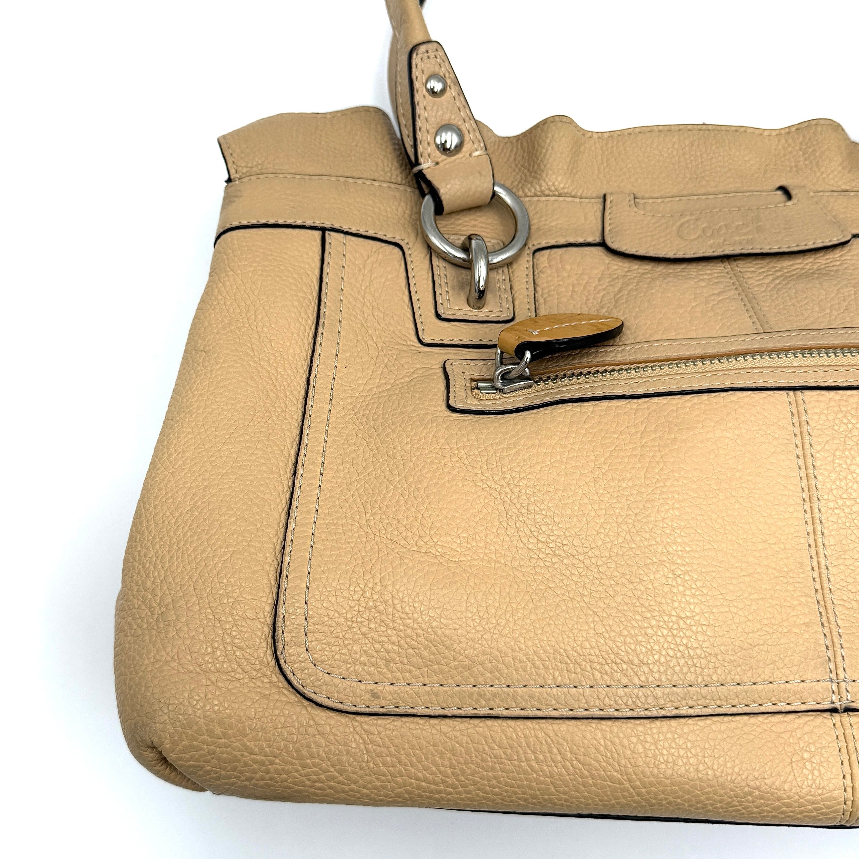 Coach Penelope handbag in cream pebble leather with rolled handles and silver-tone hardware against a white background.