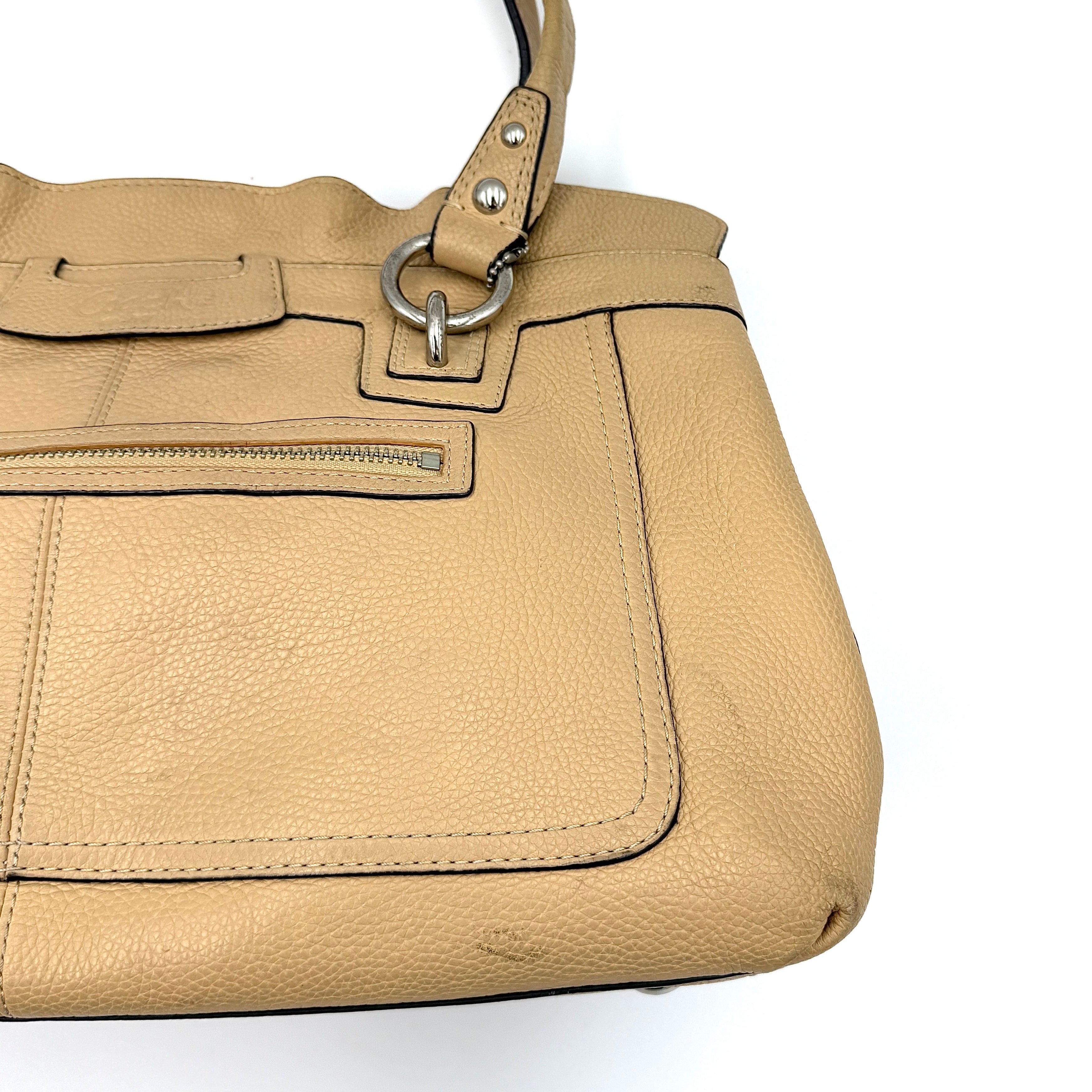 Coach Penelope handbag in cream pebble leather with rolled handles and silver-tone hardware against a white background.